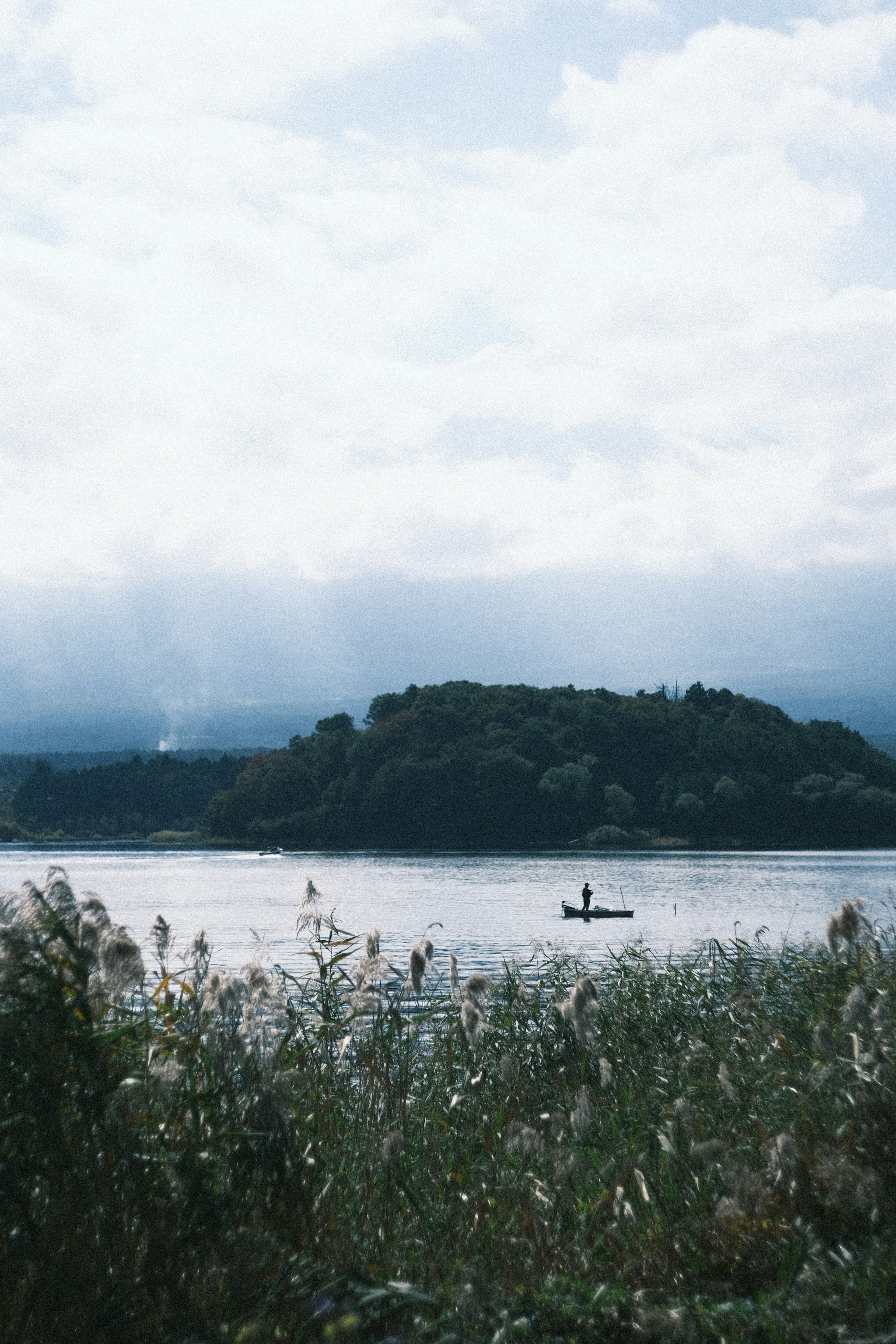 Landschaftsansicht eines ruhigen Sees mit einer kleinen Insel und einer Person im Kajak