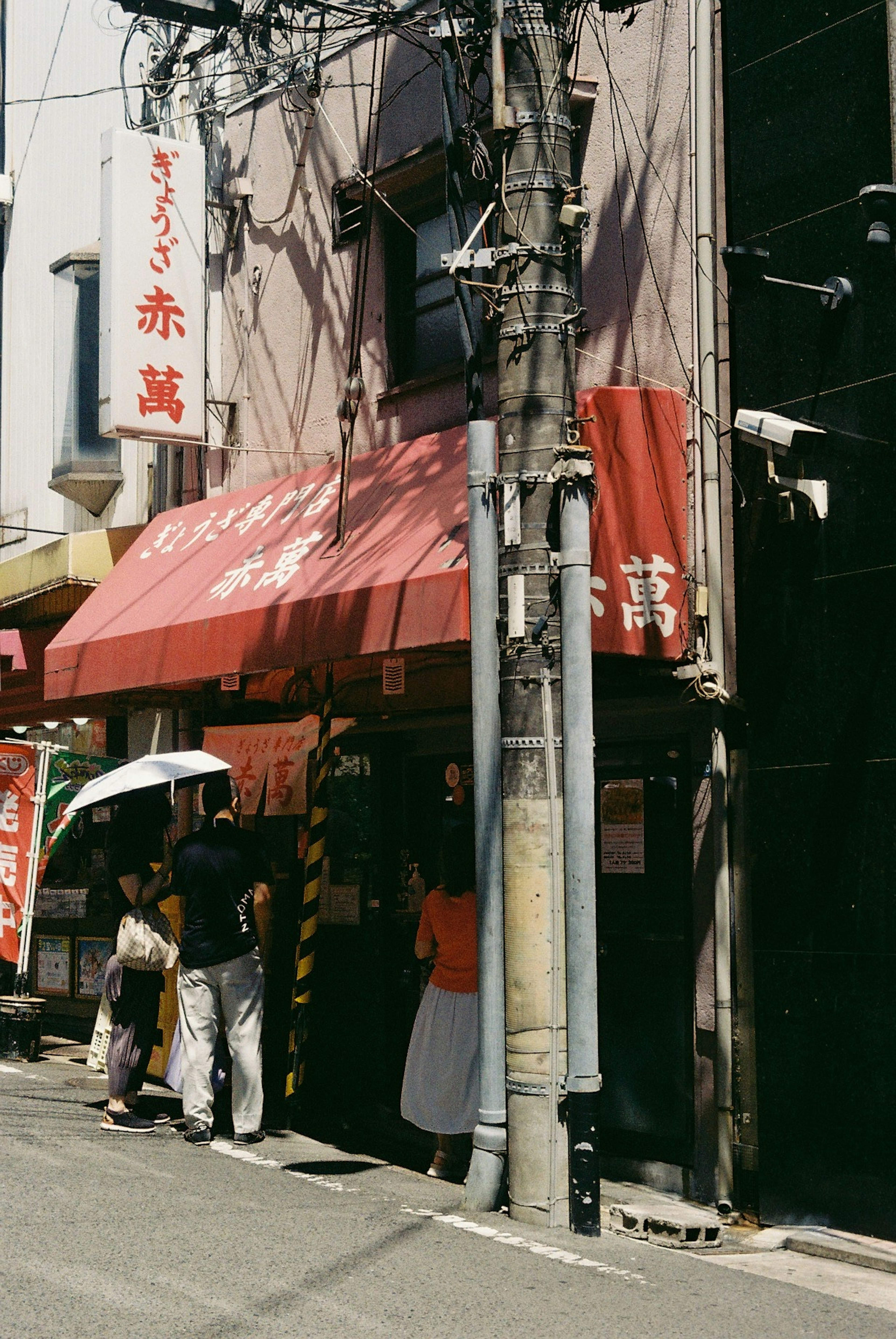 Exterior of a restaurant with a red awning and people outside