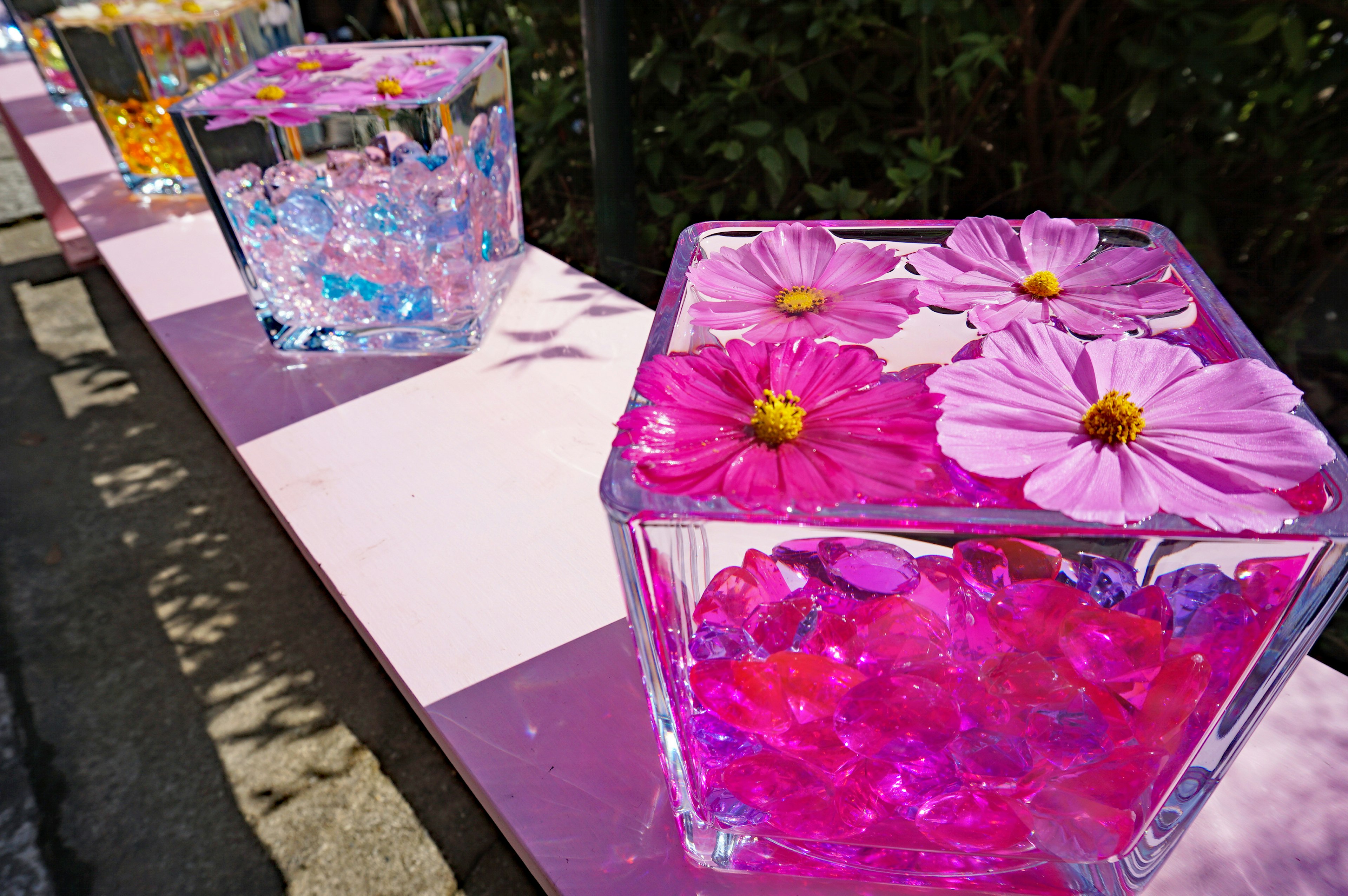 Clear containers filled with pink flowers and colorful decorations