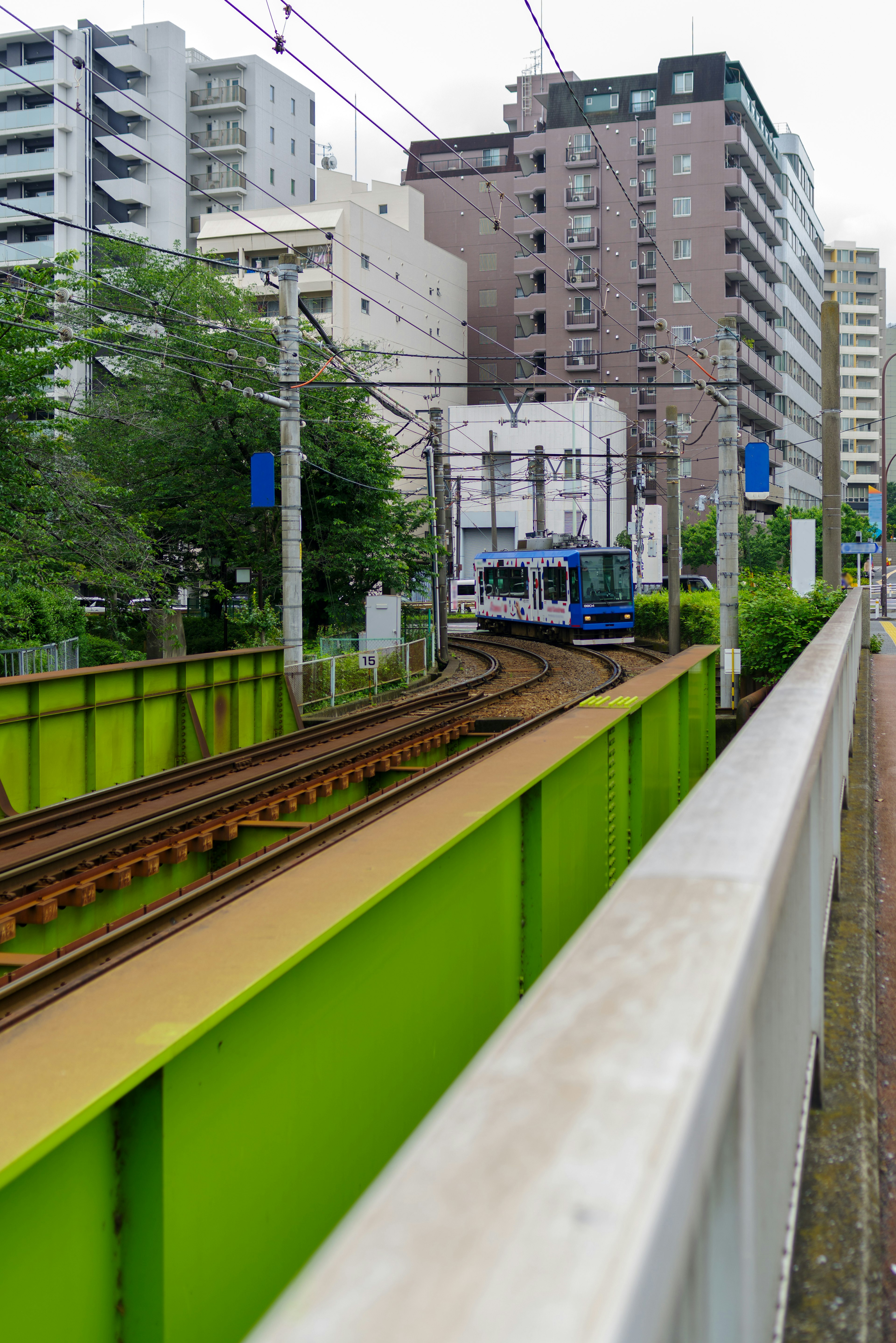 Urban landscape featuring green guardrails and railway tracks