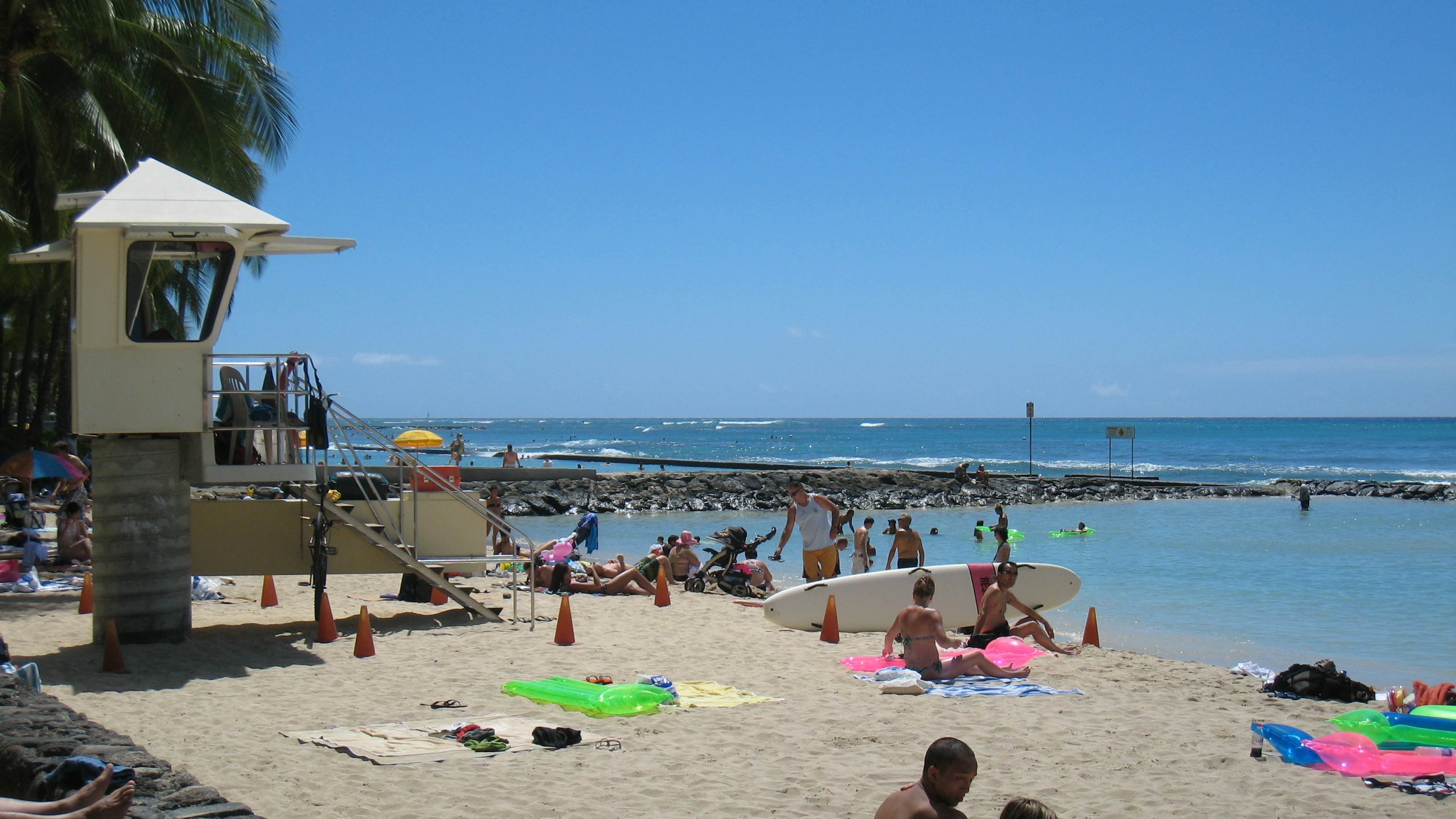 Orang-orang bersantai di pantai dengan langit biru dan lautan