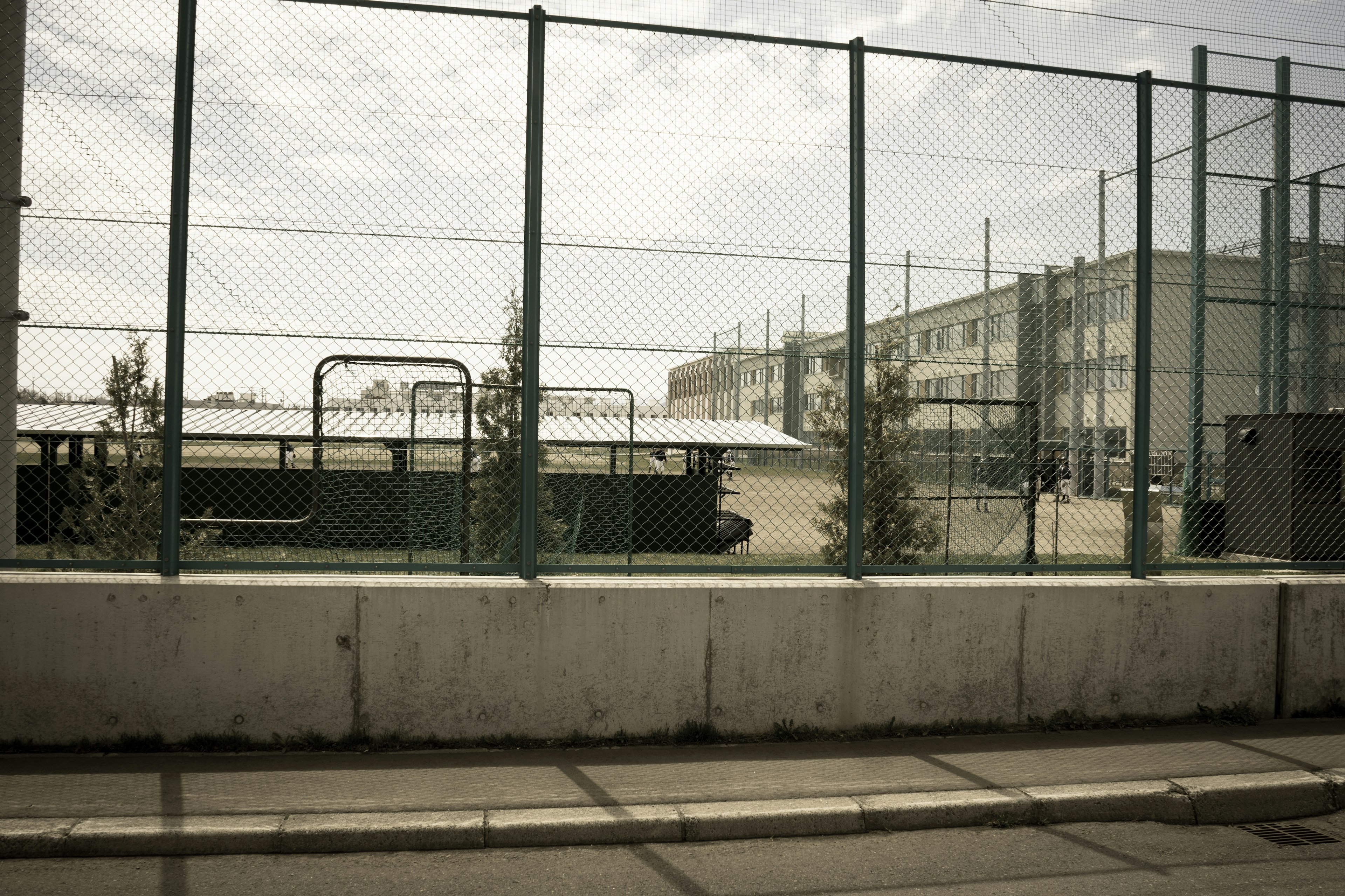 Vue d'une cour d'école et d'un bâtiment à travers une clôture