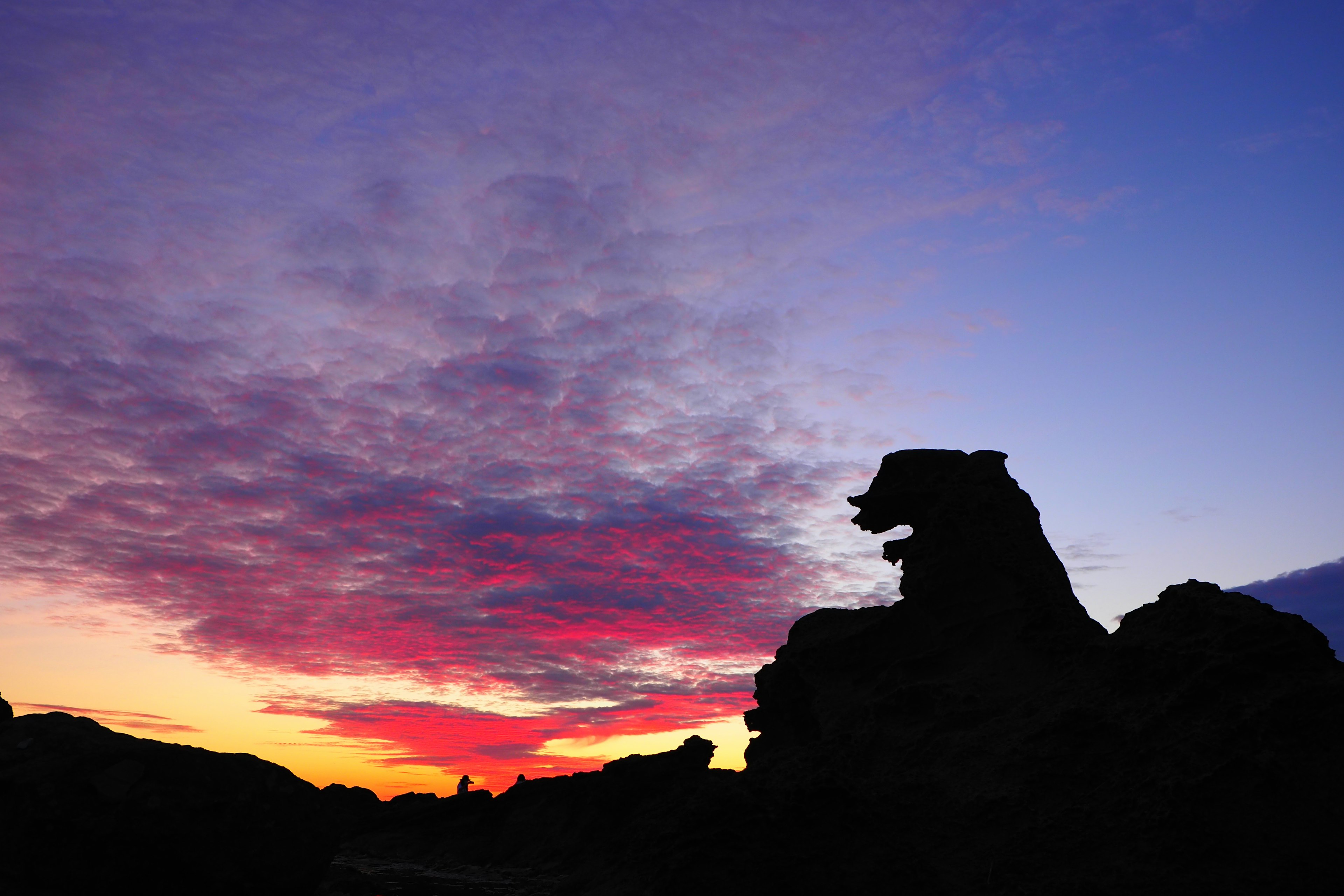 Silhouette of rock formation against a vibrant sunset sky