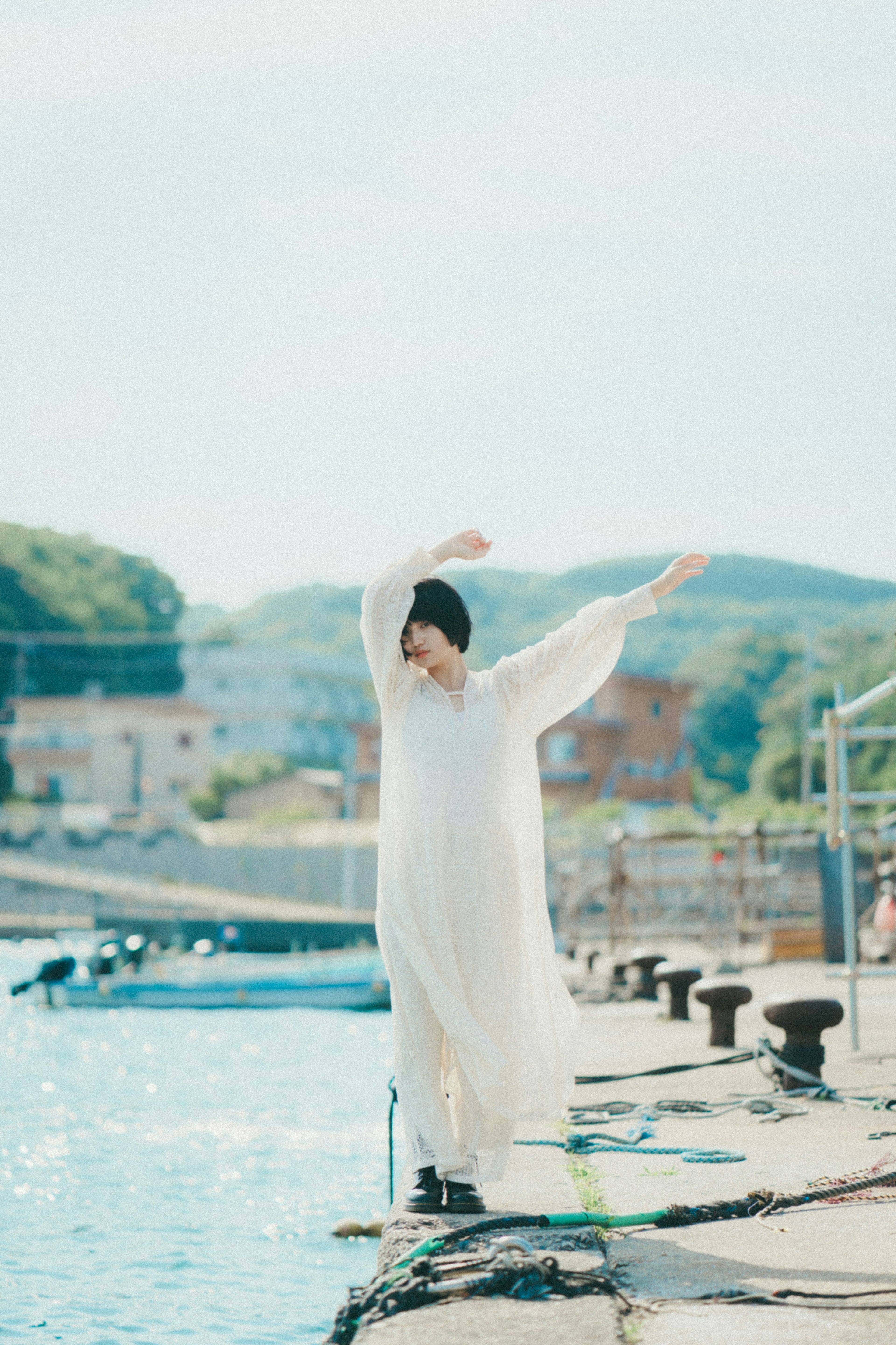 Person in weißem Outfit, die am Wasser posiert