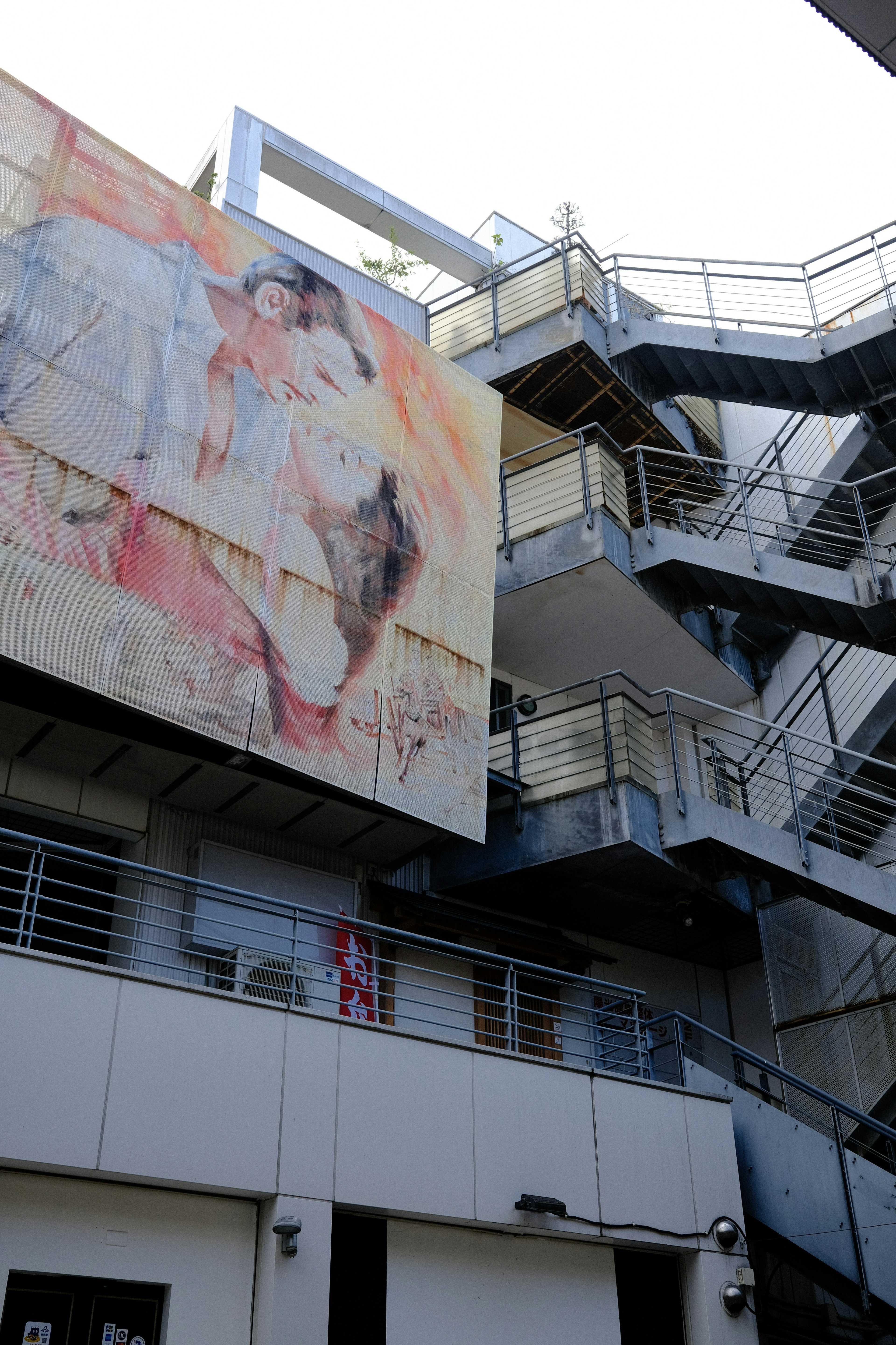 Une grande fresque sur l'extérieur d'un bâtiment avec des escaliers métalliques visibles