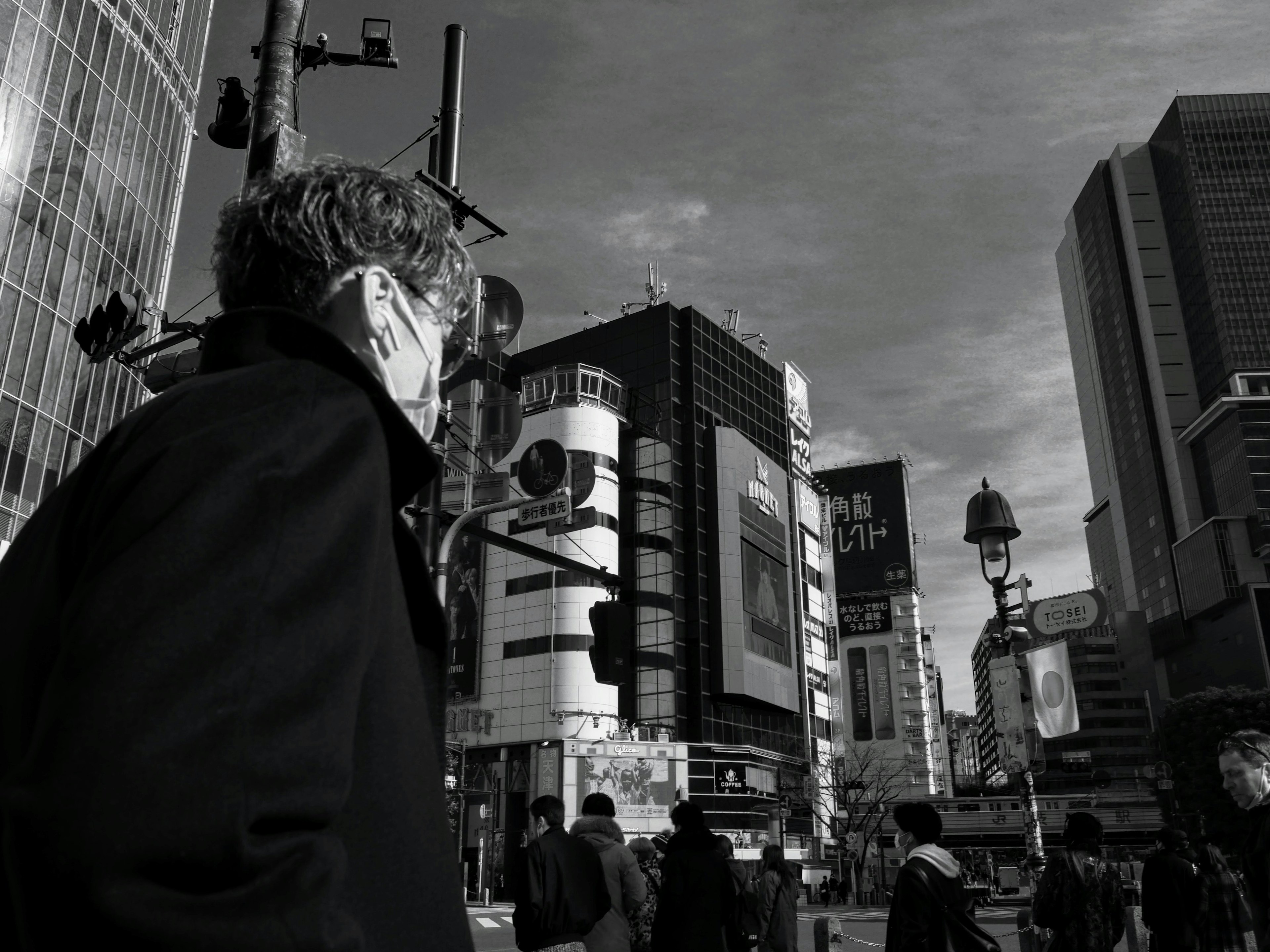 Homme portant un masque regardant une intersection animée en noir et blanc