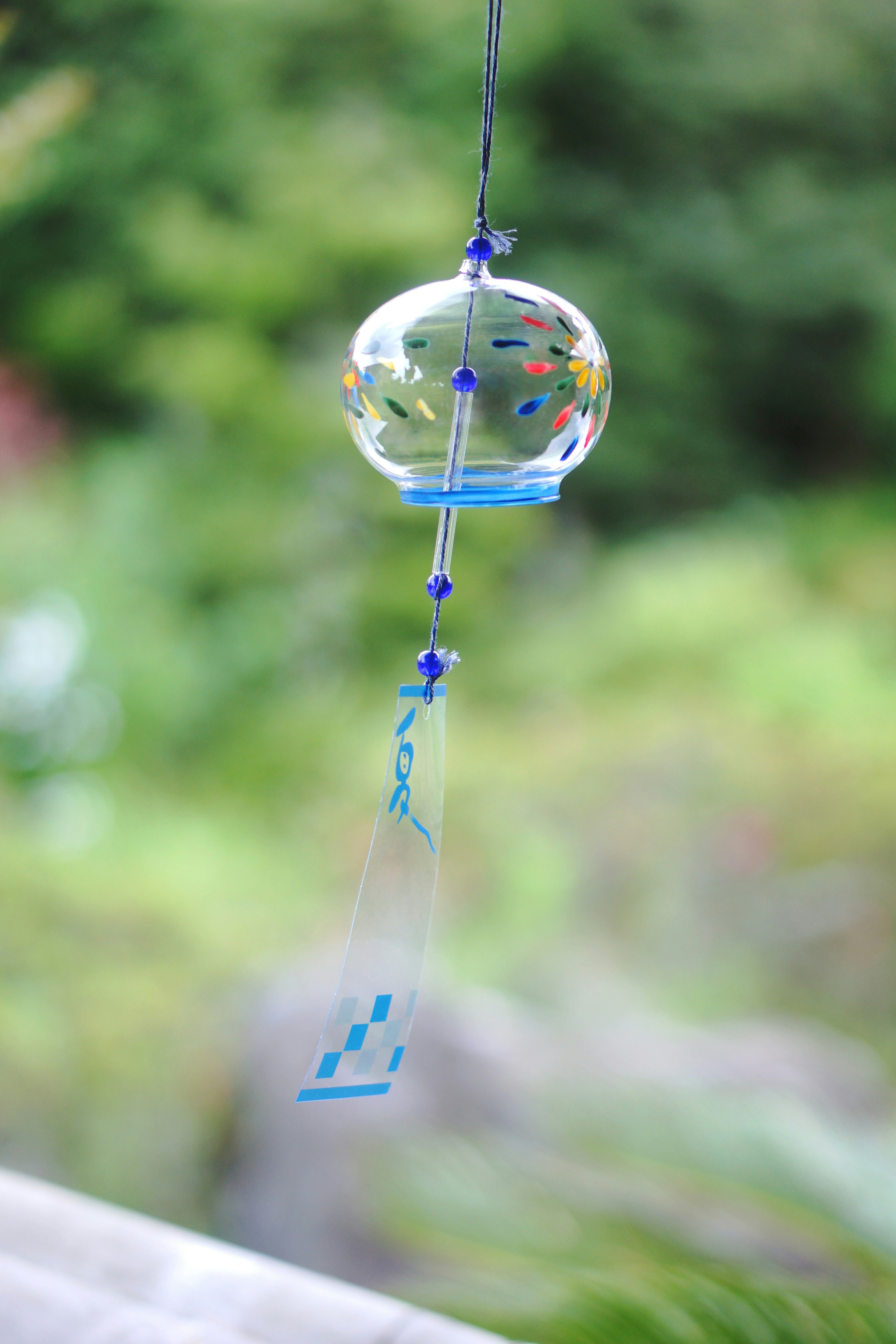 Blue wind chime hanging against a green background