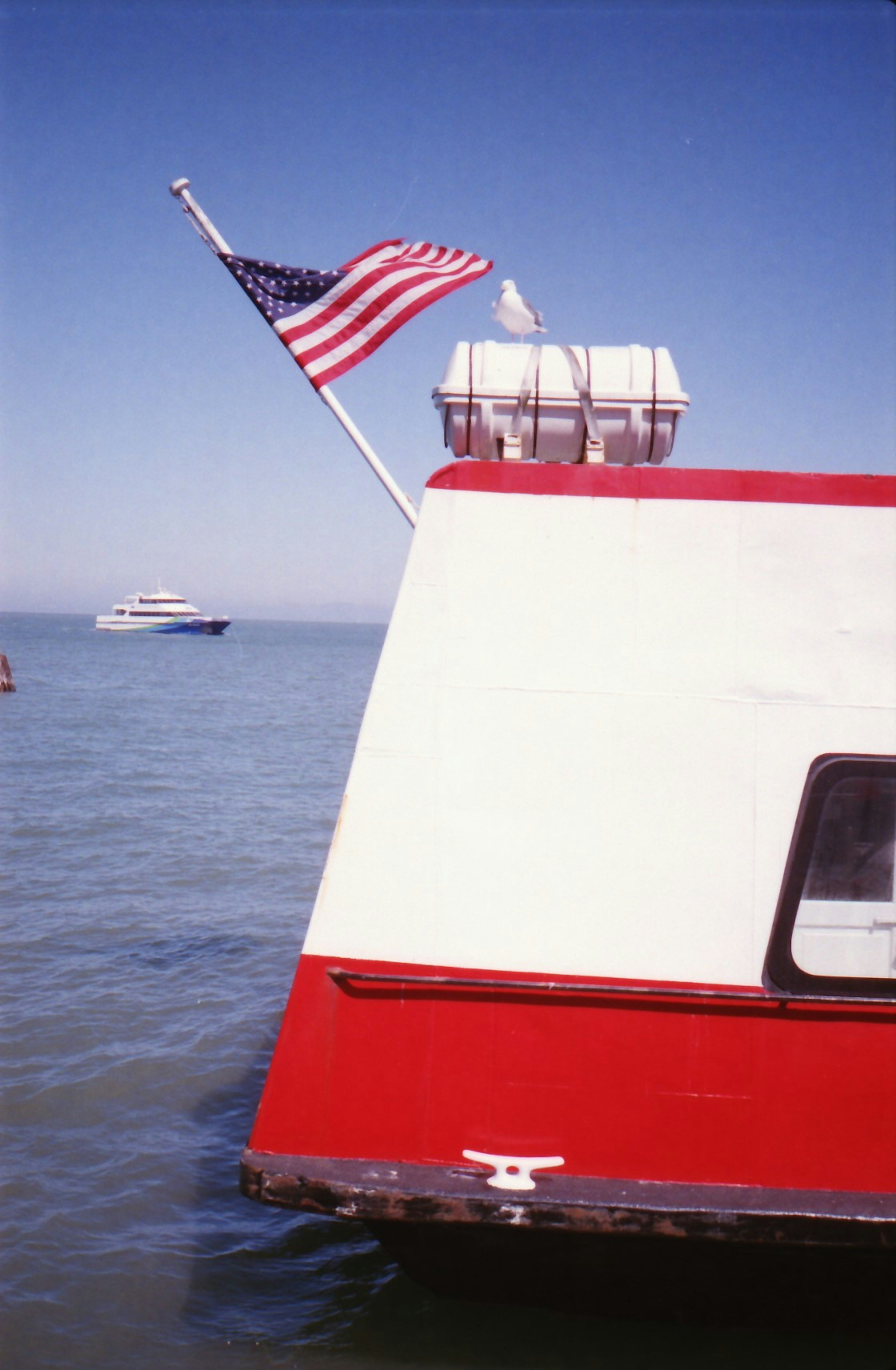 Barco rojo con bandera americana en la parte trasera en un entorno acuático sereno