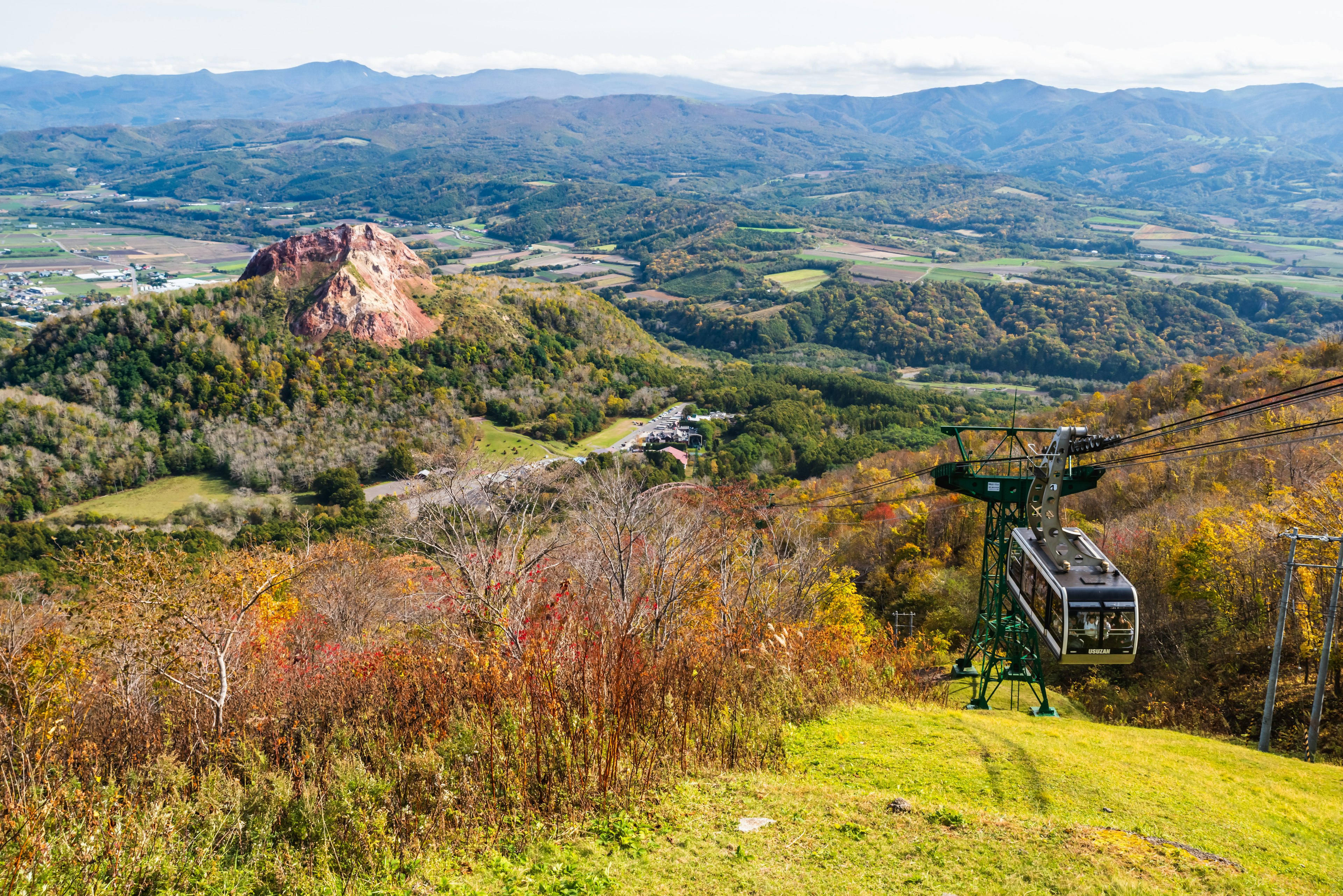 Vista panoramica di montagne autunnali e funivia formazione rocciosa rossa e paesaggio verde