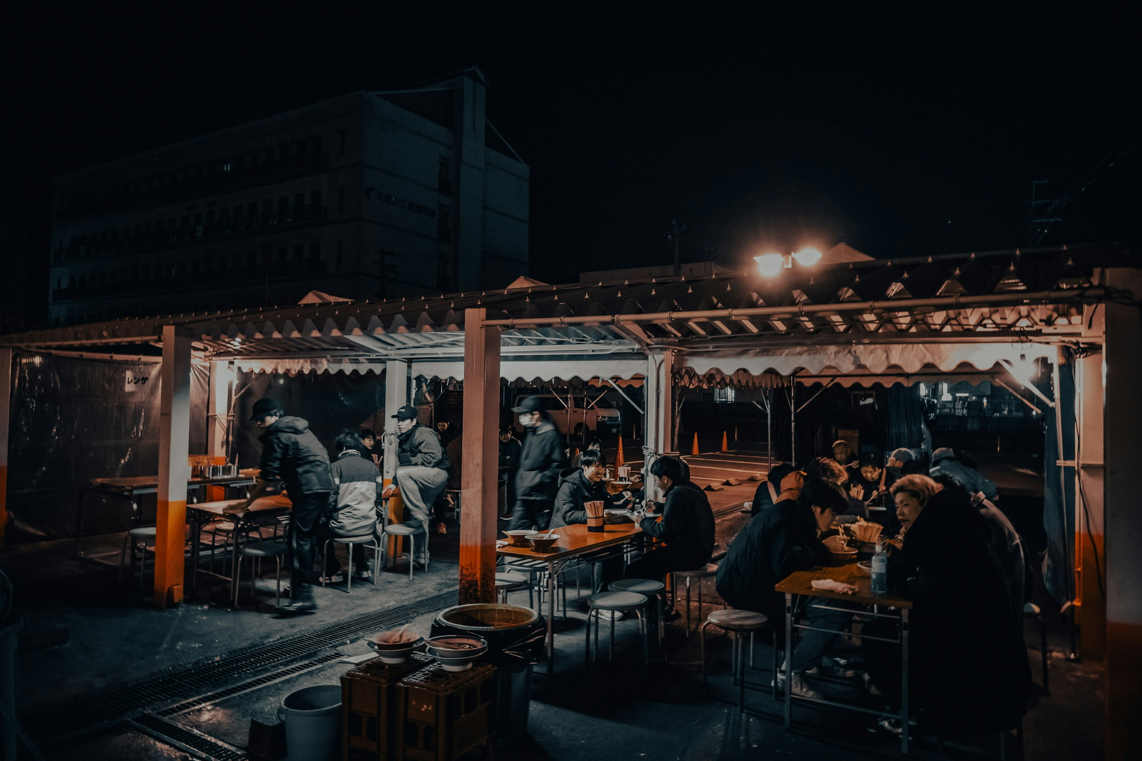 Personas cenando en un puesto de comida callejera de noche