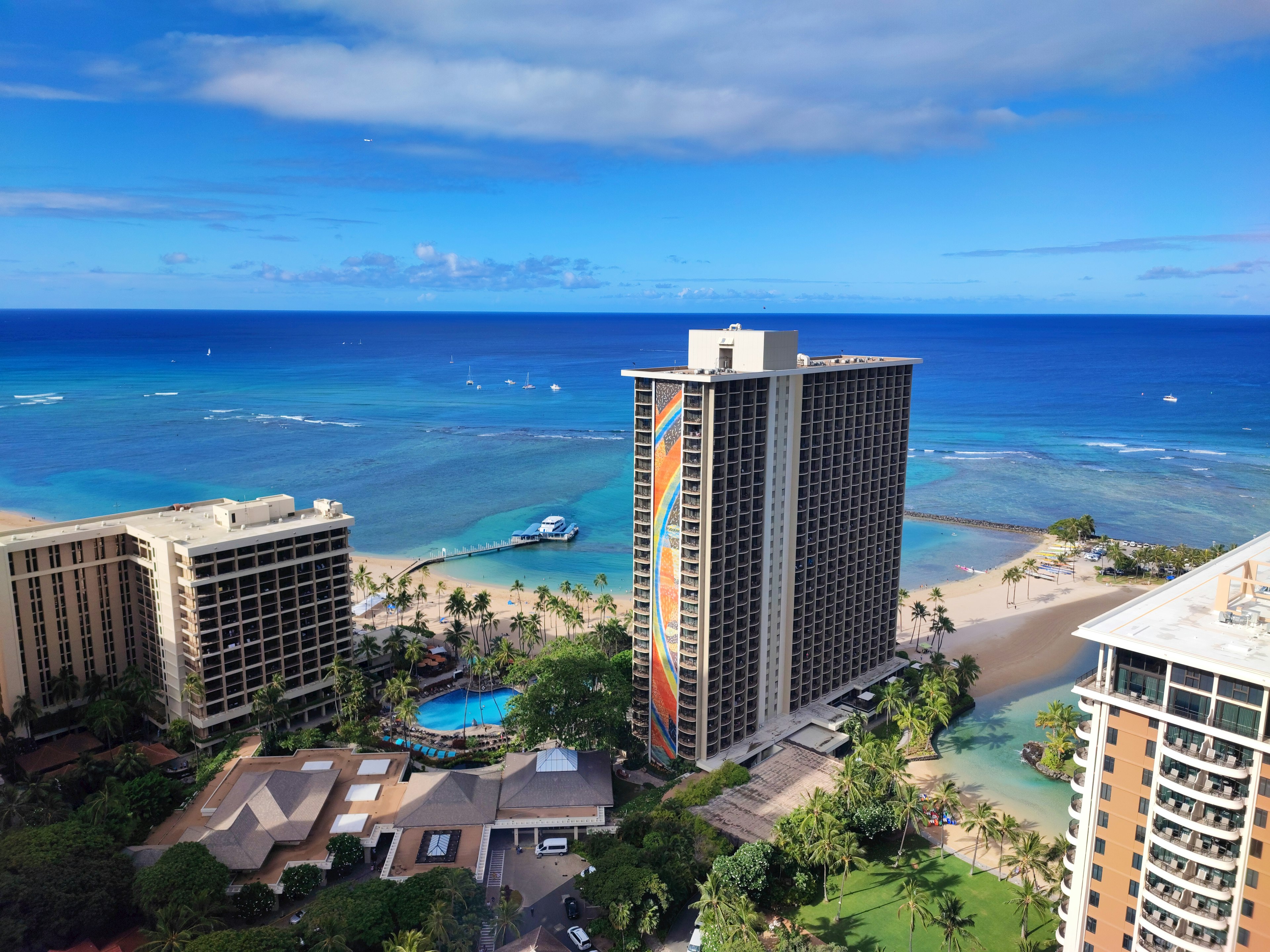 Pemandangan gedung pencakar langit dengan latar belakang laut biru dan langit menampilkan garis pantai Honolulu dan area resor