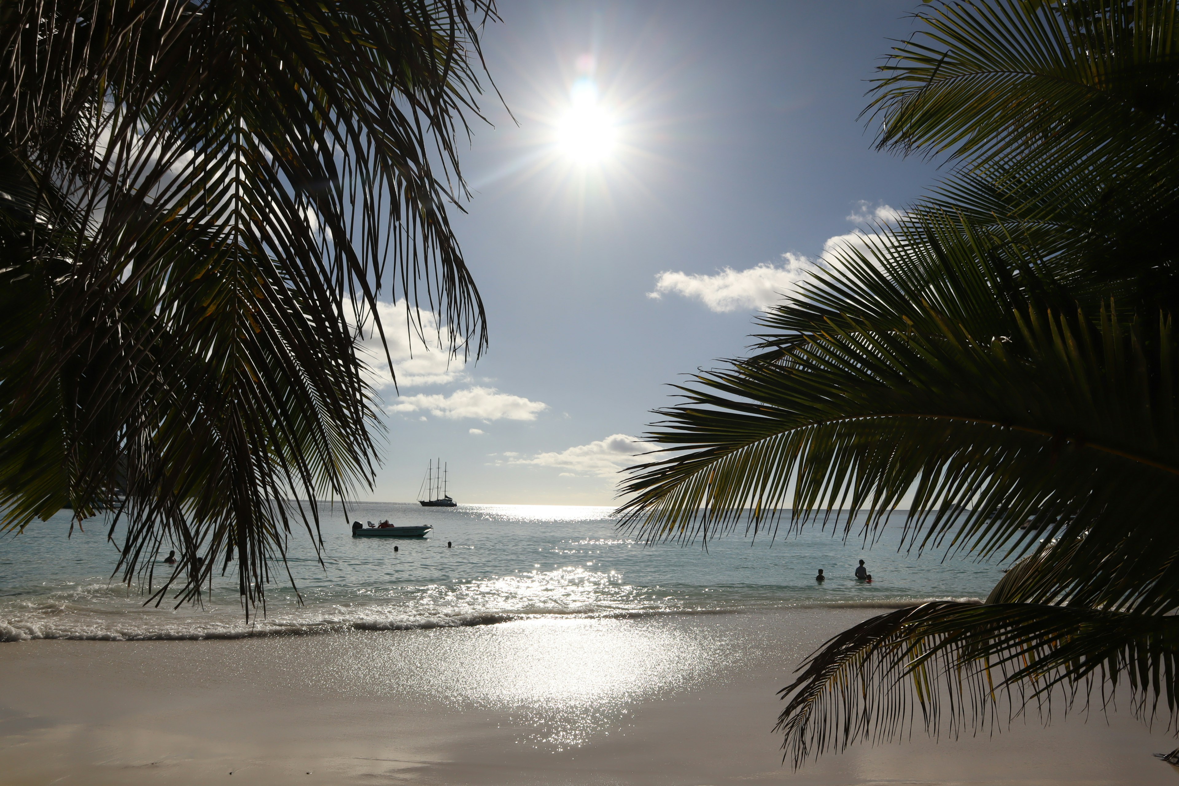 Escena de playa con sol brillante sobre el mar azul y arena blanca