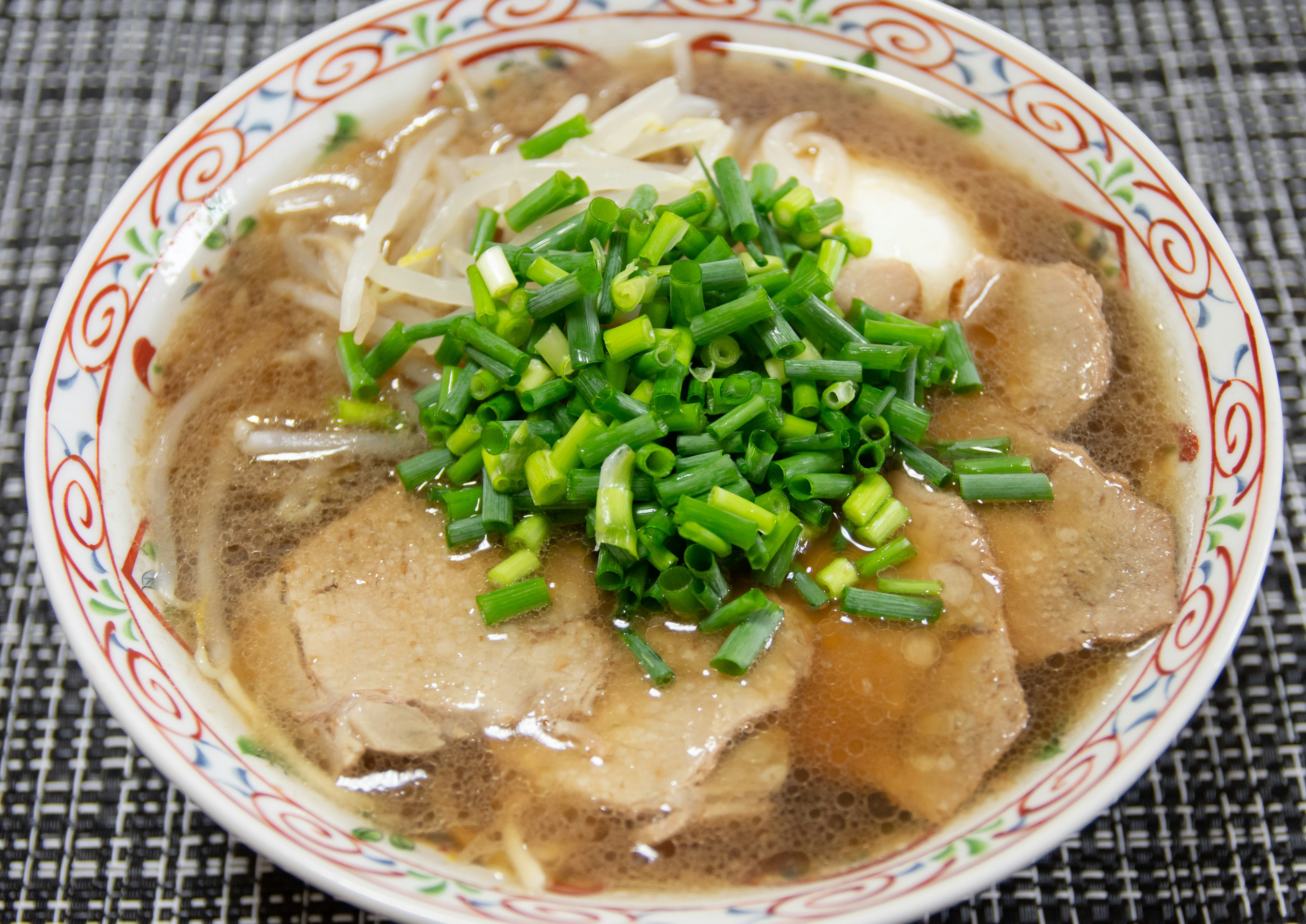 Ciotola di ramen con fette di carne e abbondante guarnizione di cipollotti