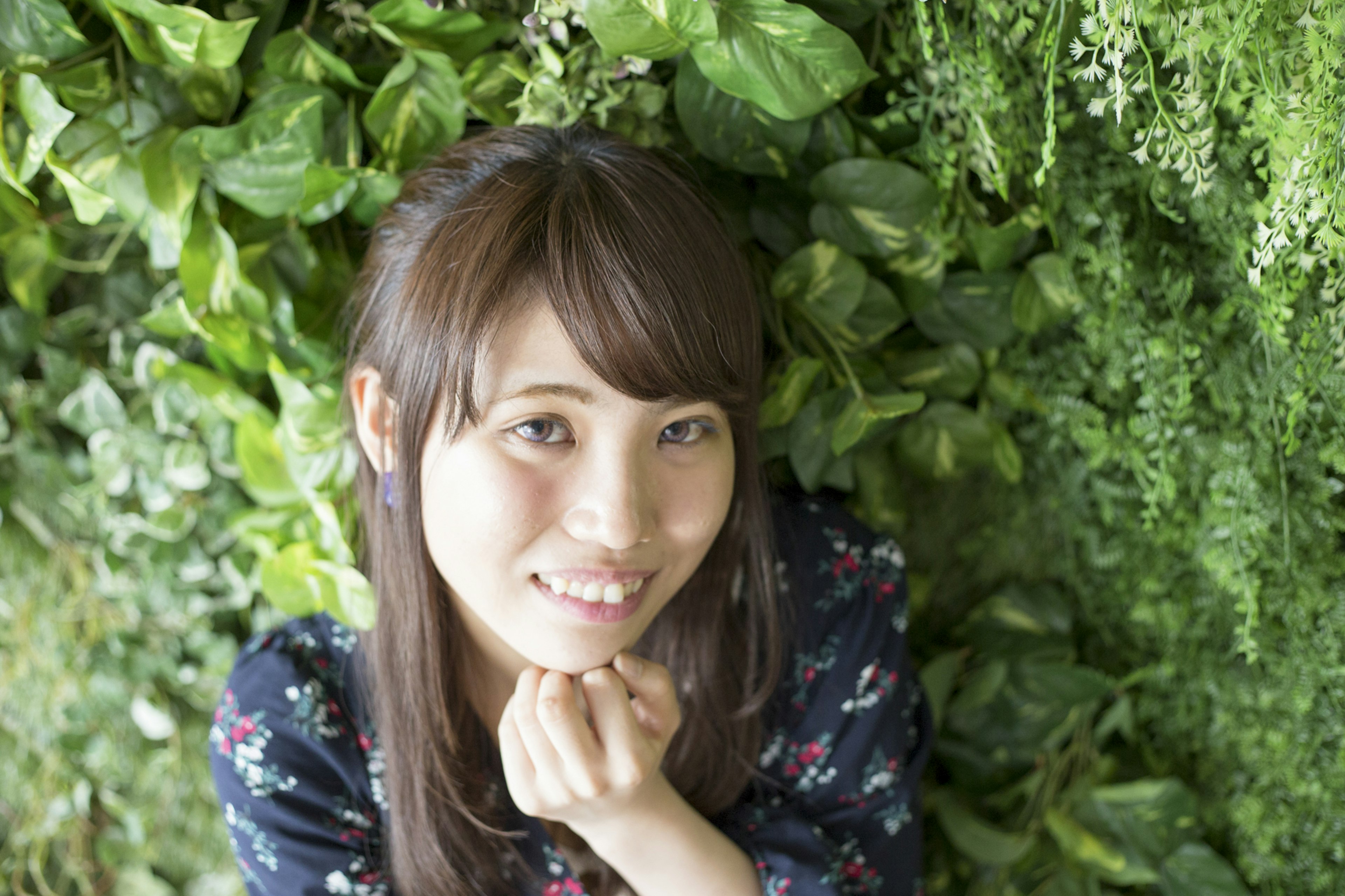 Portrait d'une jeune femme souriante devant un mur vert