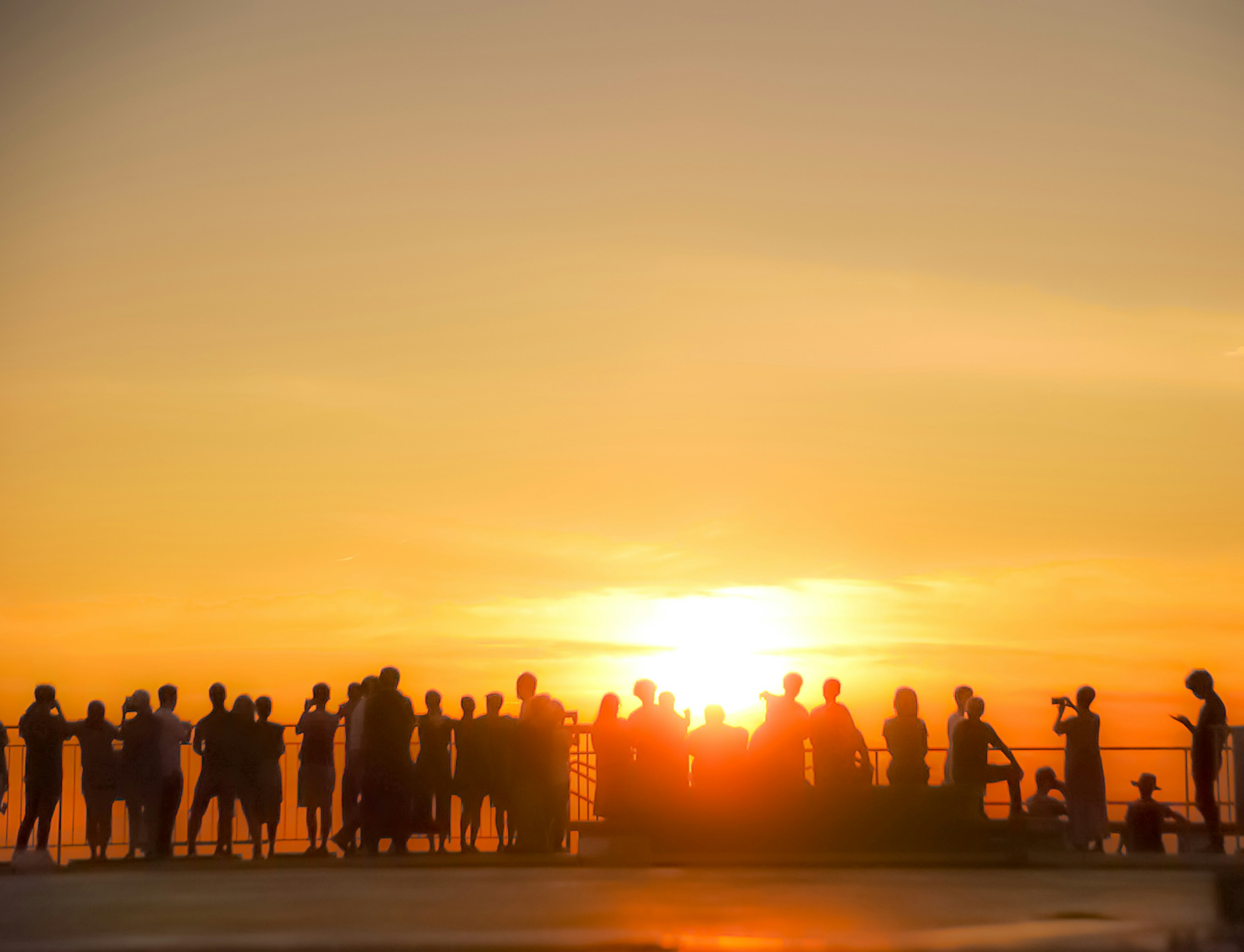 夕日を背景にした人々のシルエットが並ぶ風景