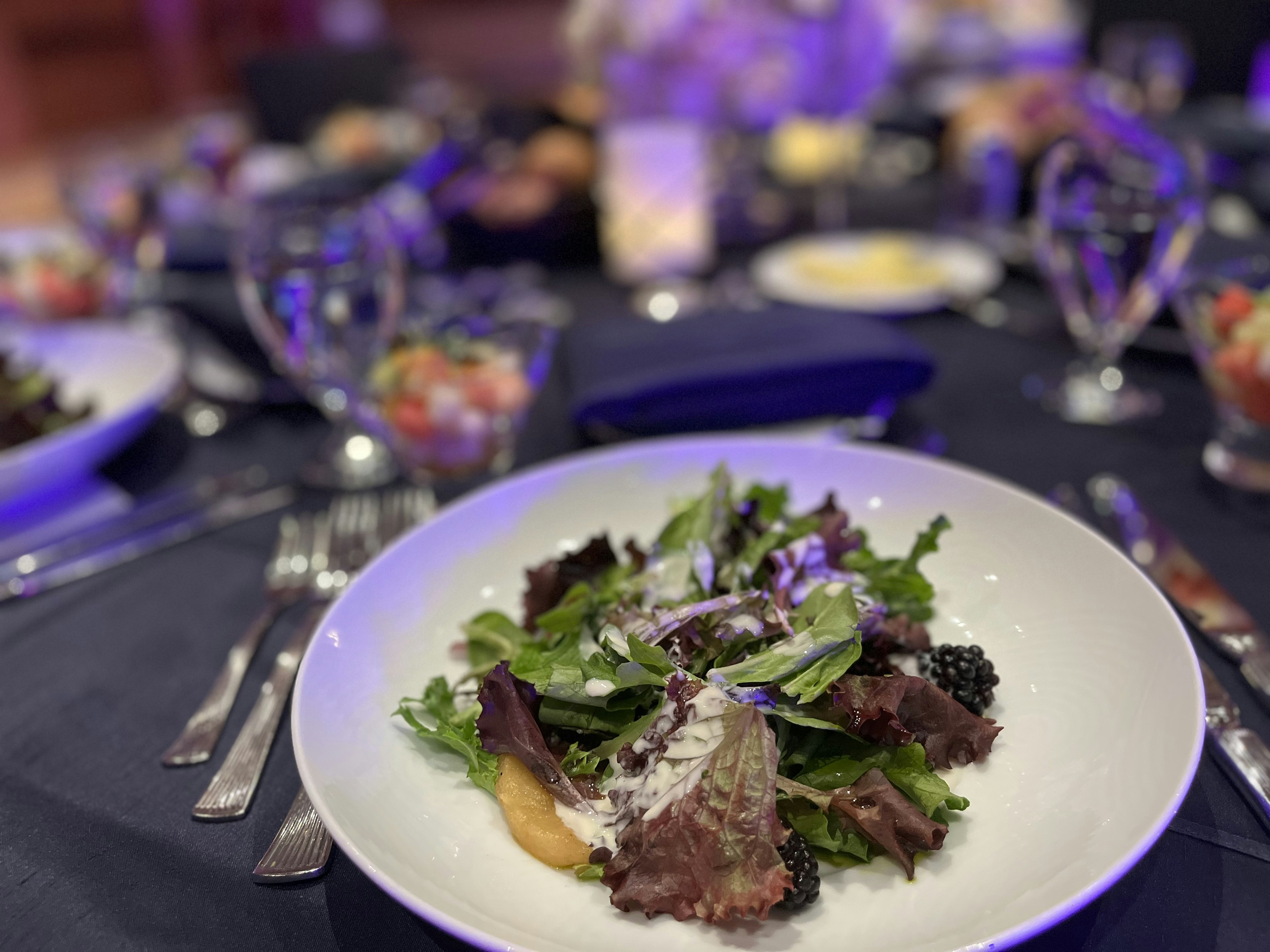 Fresh salad plate at the center of a table setting with various dishes in the background