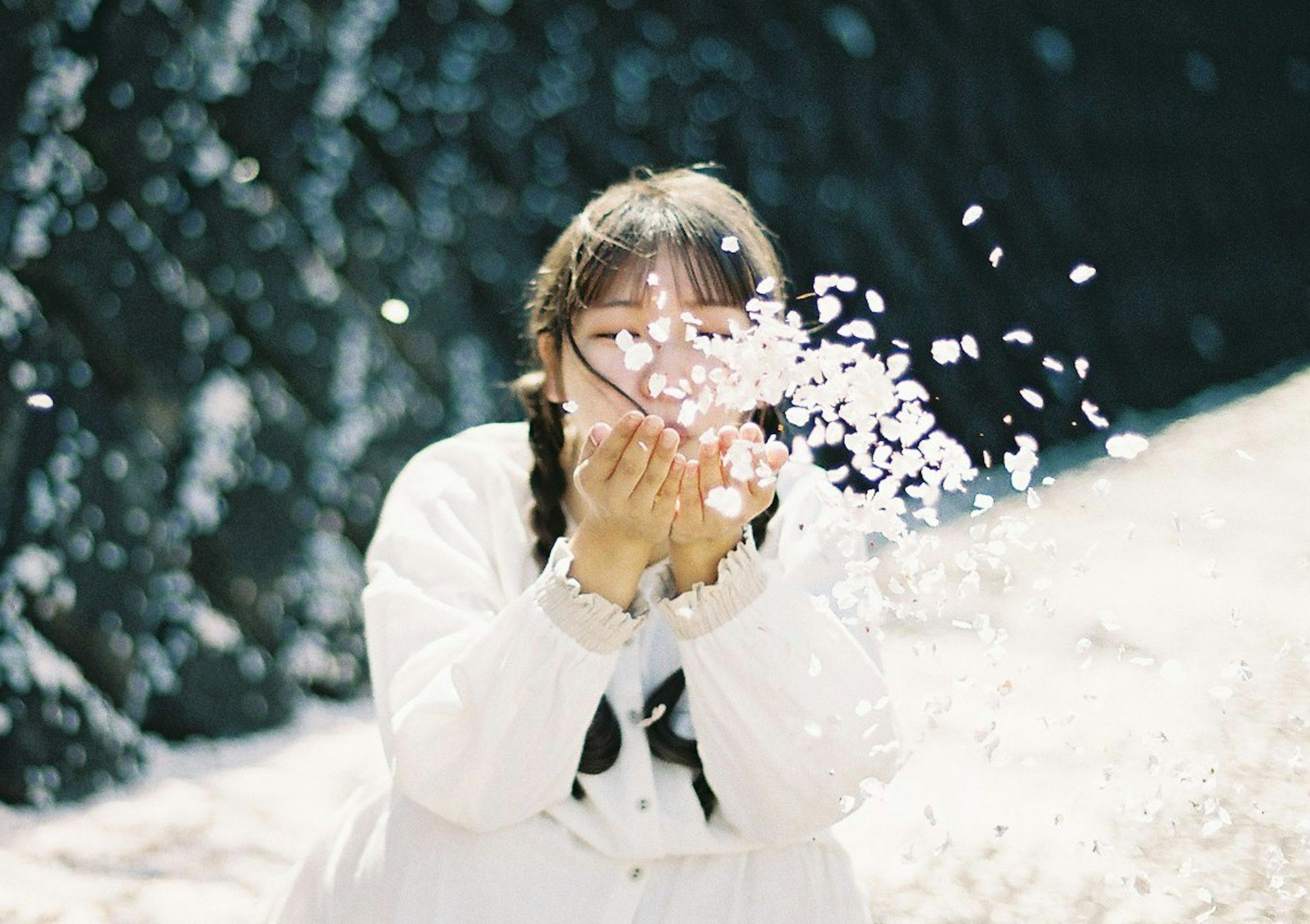 Girl blowing petals from her hands in a natural setting