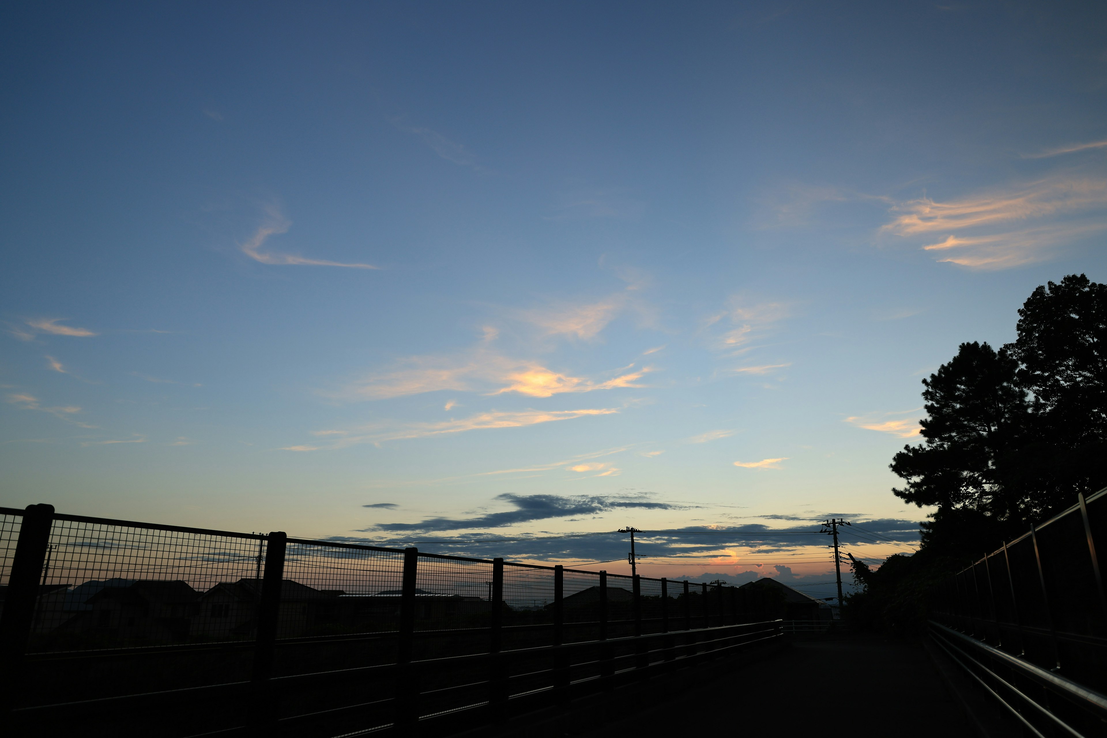 Weg unter einem blauen Himmel mit Wolken und Sonnenuntergangsfarben