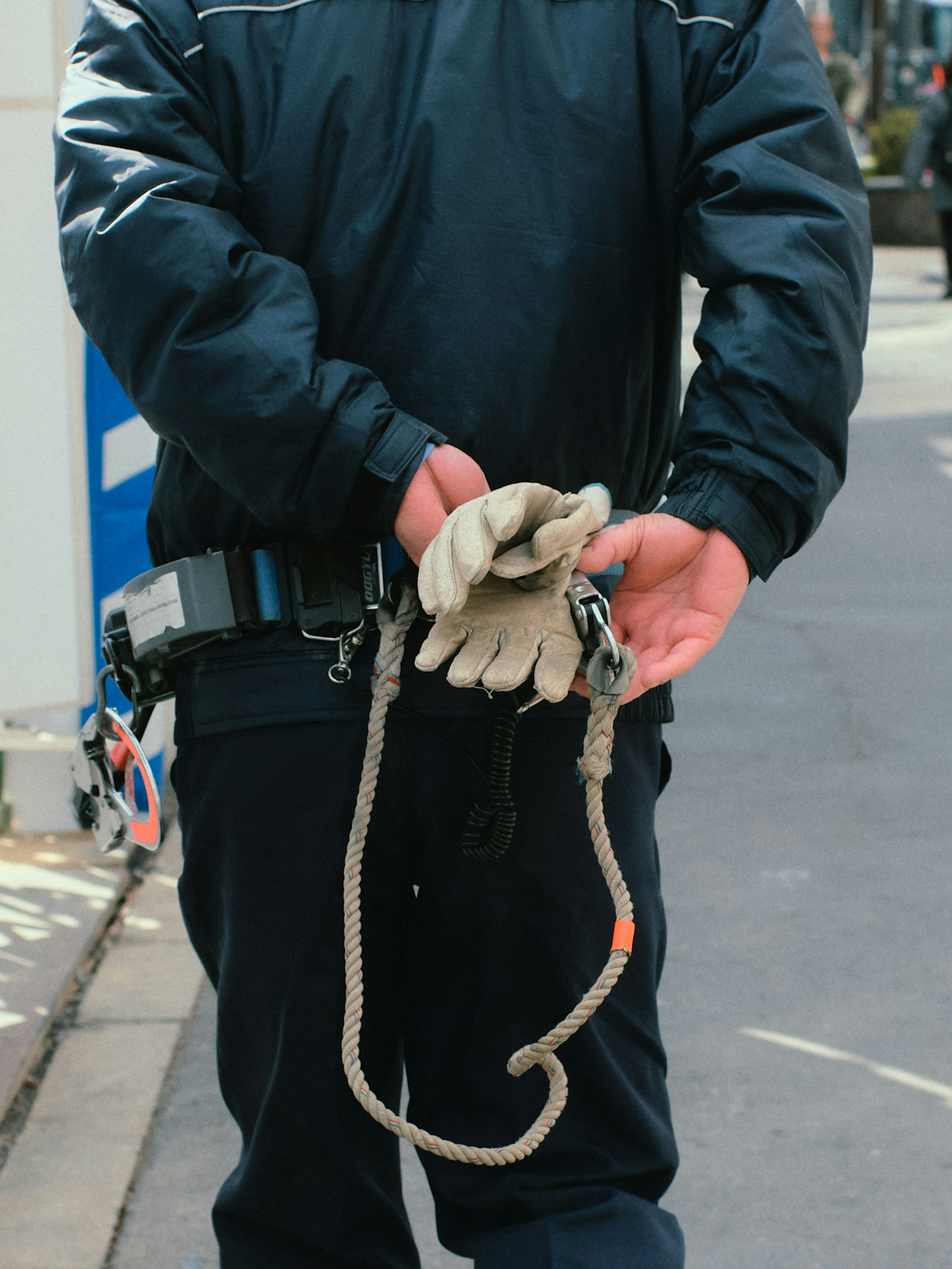 A security officer holding gloves with a rope leash