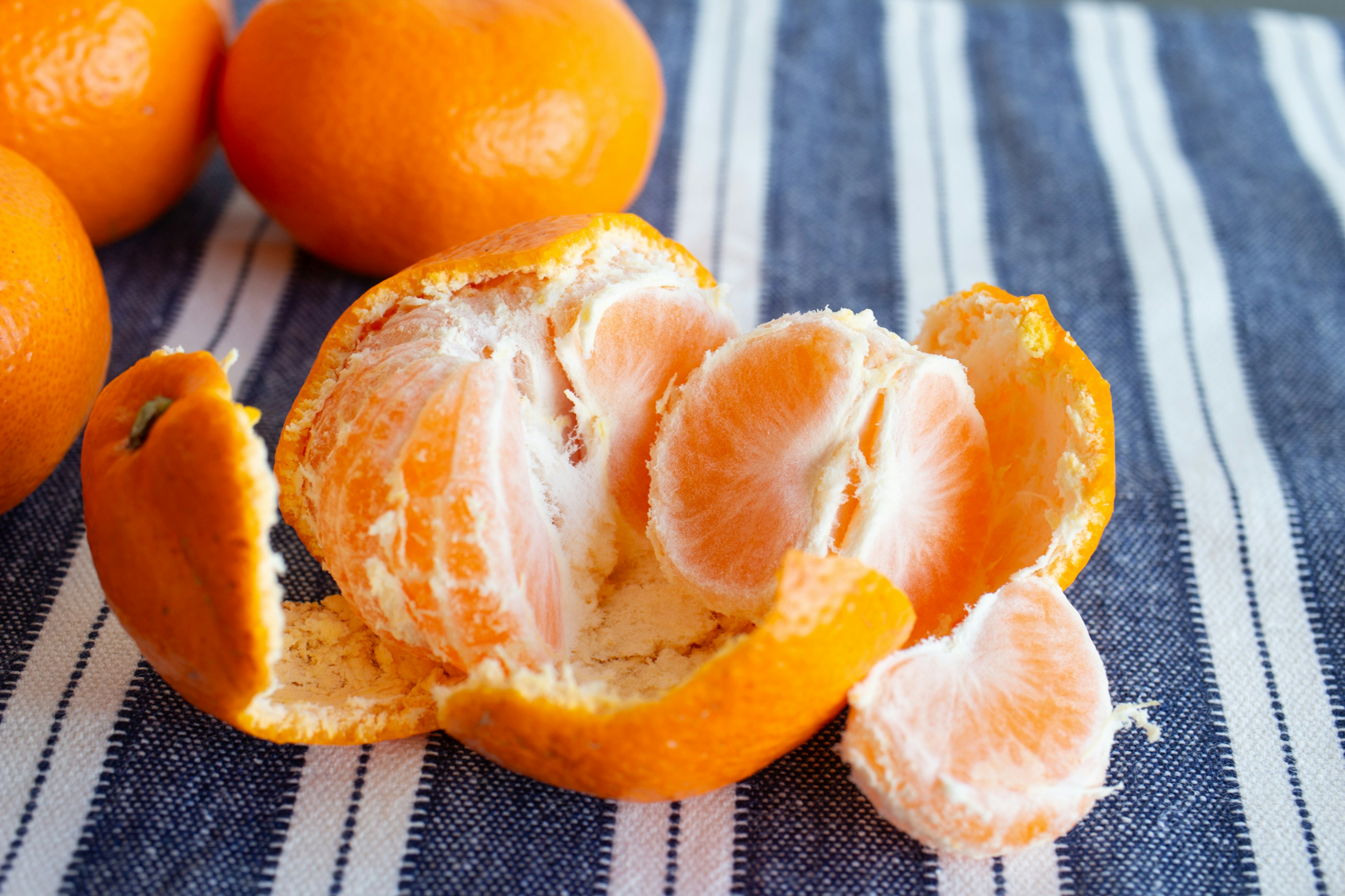 Peeled tangerine with exposed juicy segments on a striped cloth