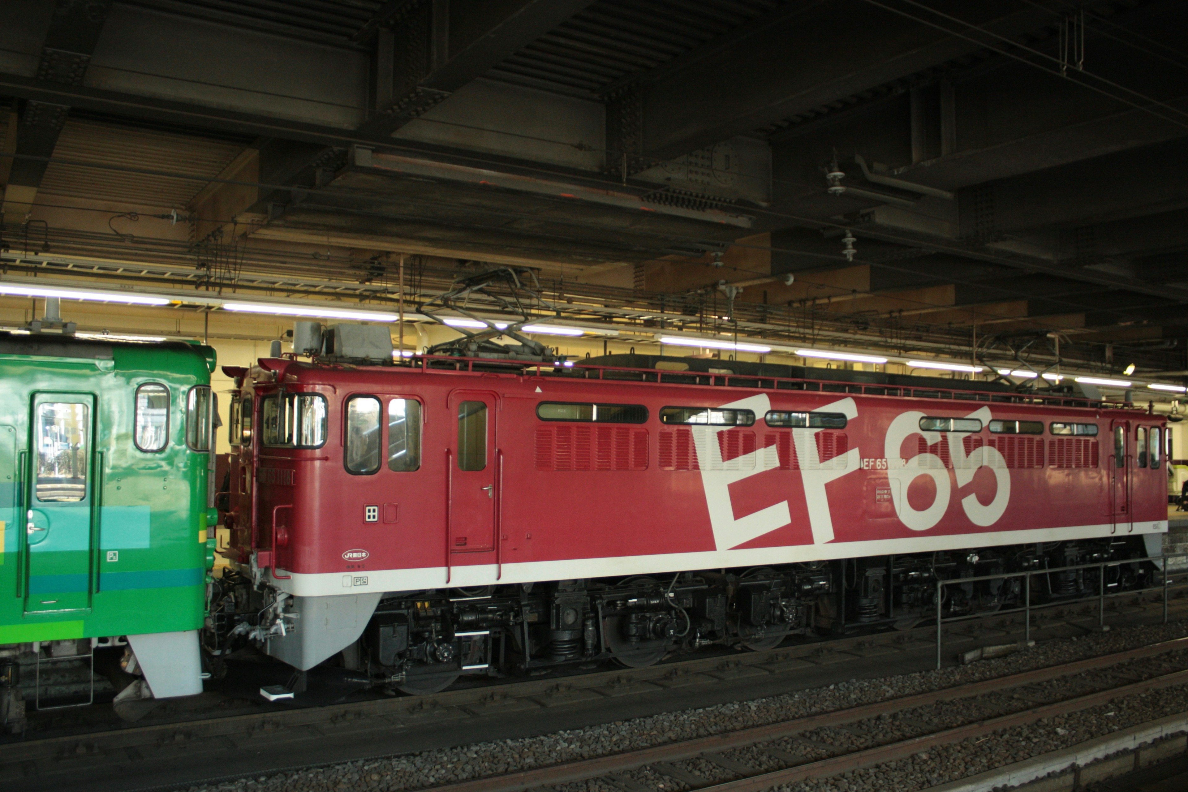 Red EF65 locomotive parked at a train station platform