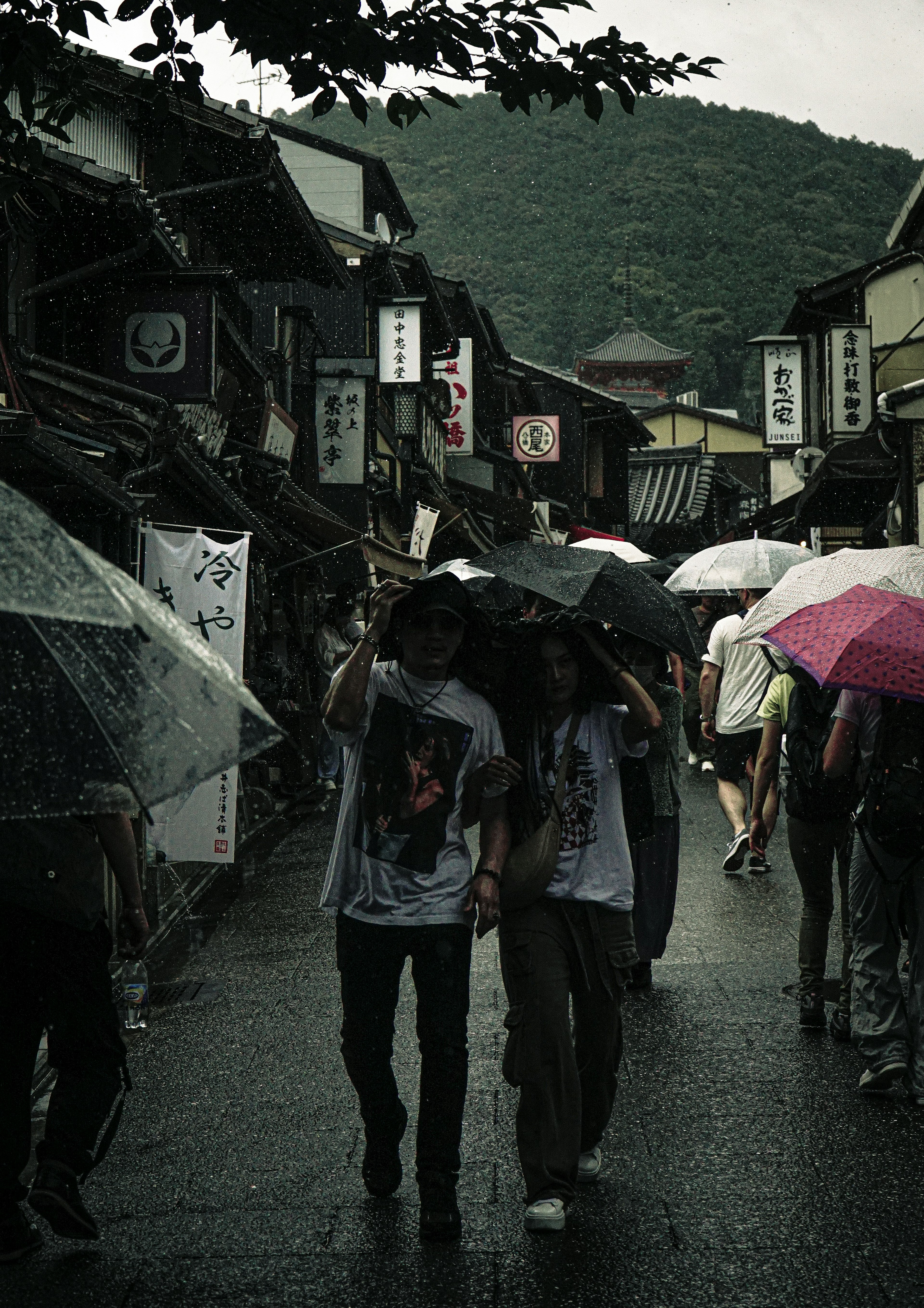 雨の中を歩く人々と傘がある古い町並み