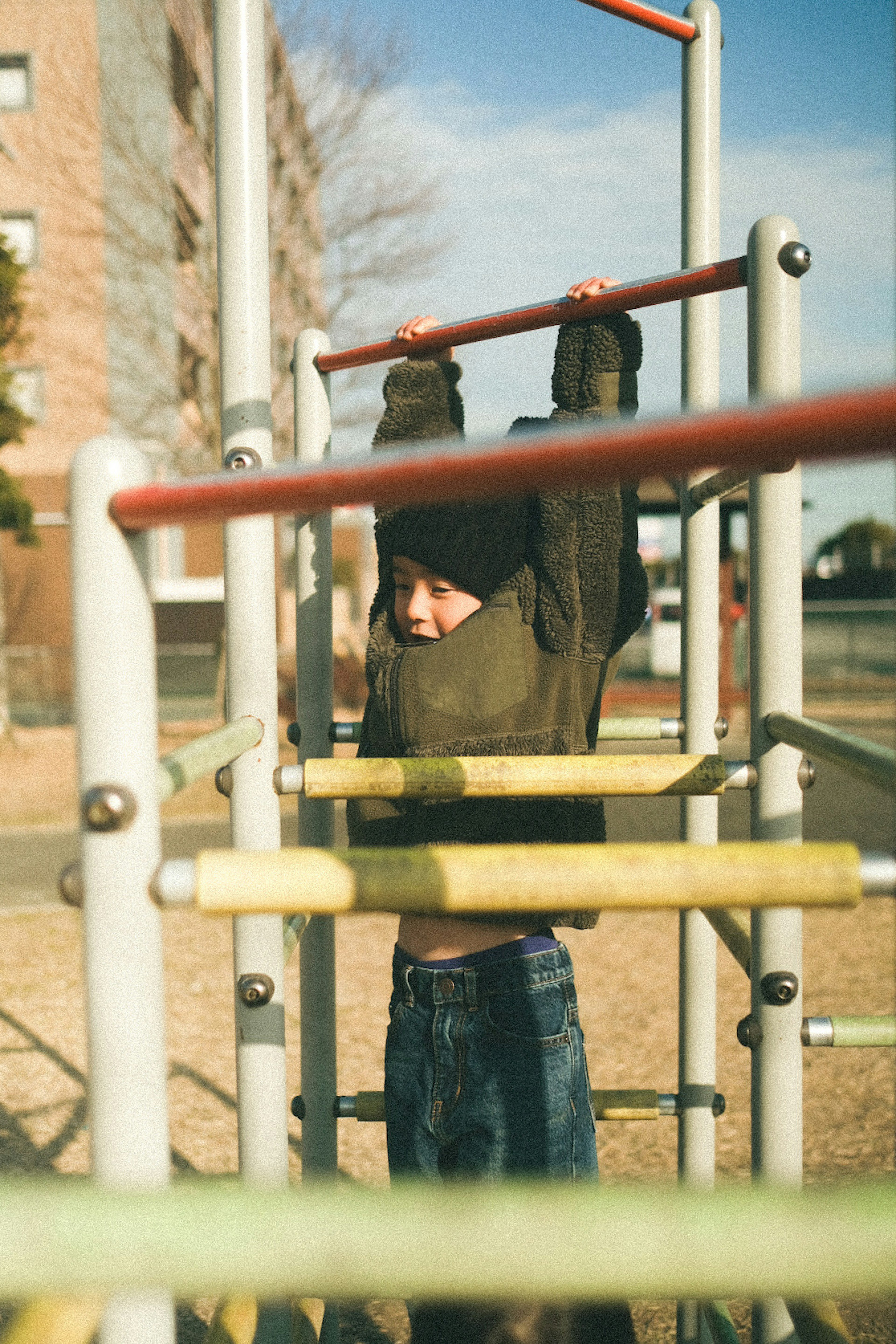 Child hanging from playground equipment in a park