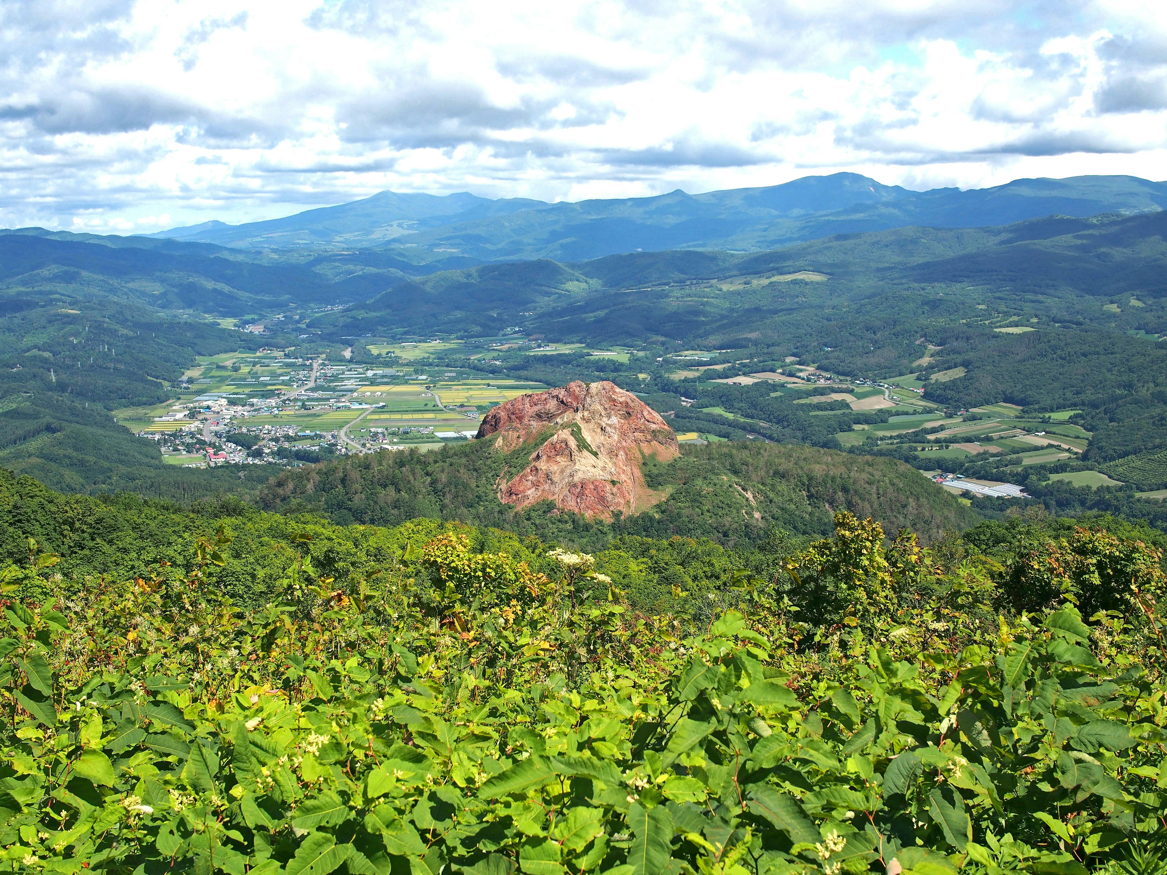 被绿色植物环绕的风景如画的山景，显眼的红色岩石