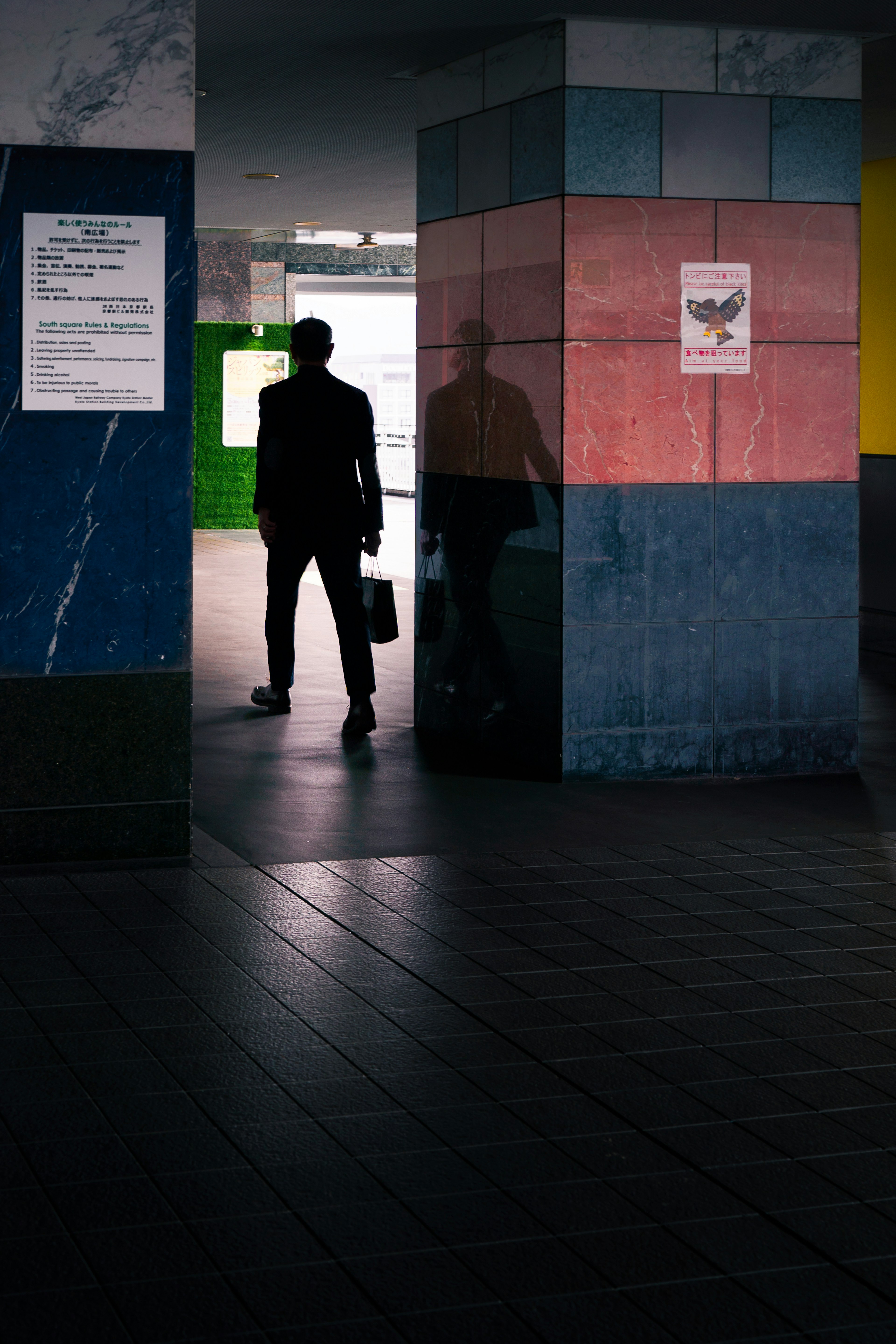 Silhouette of a person walking between colorful pillars in a dimly lit space