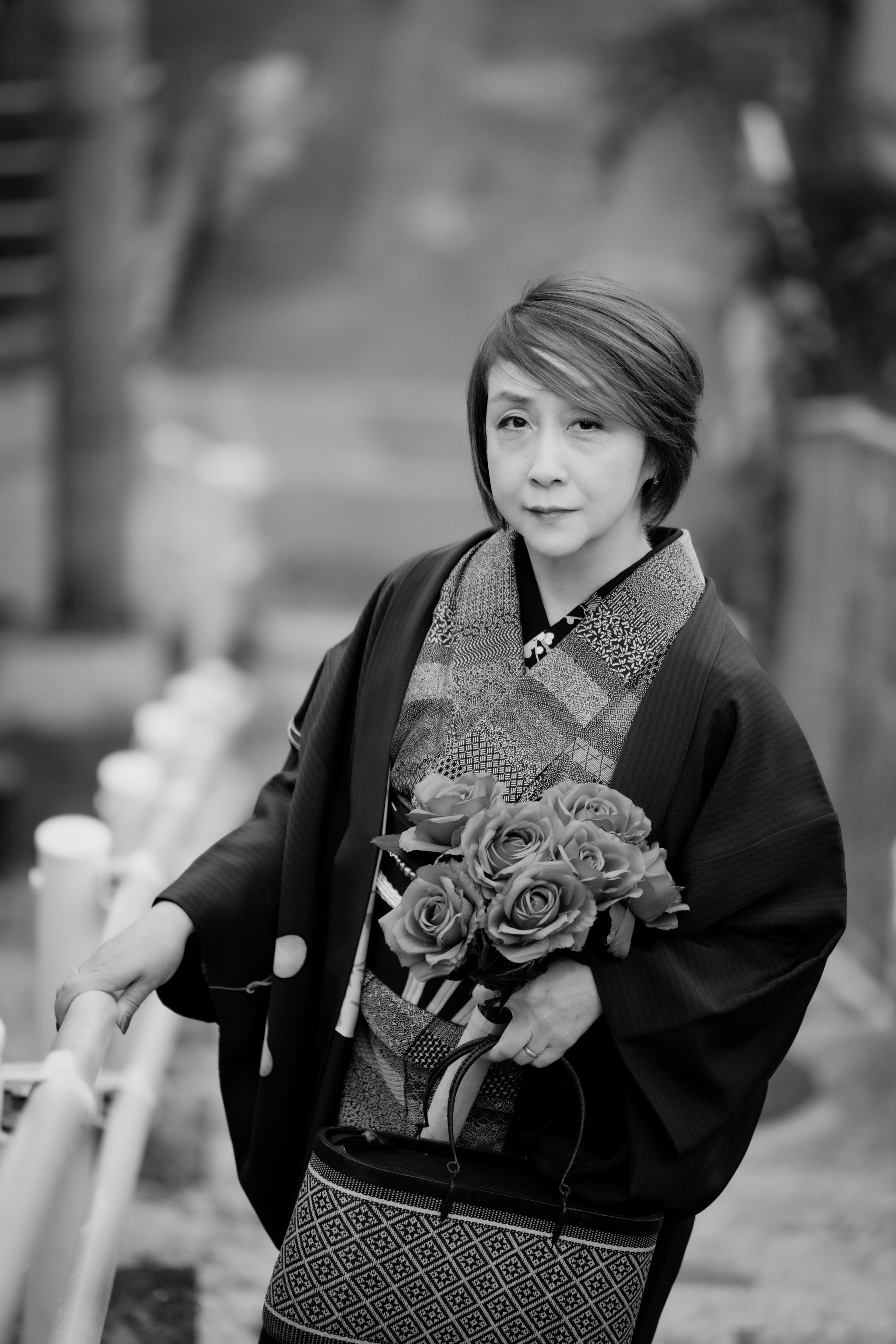 Un ragazzo in kimono bianco e nero con un bouquet di fiori sorridente