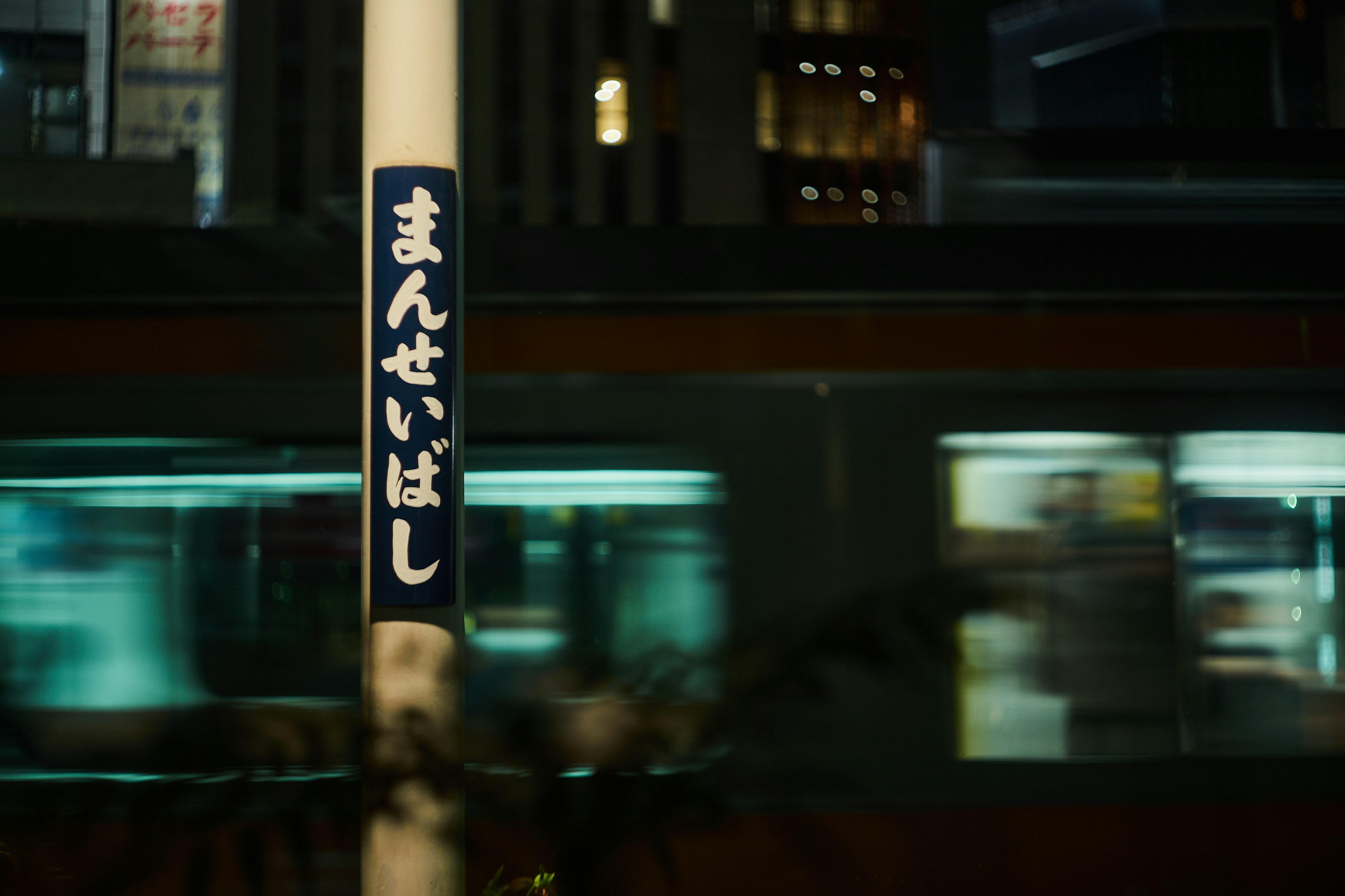 Night urban scene featuring a moving train and a station sign