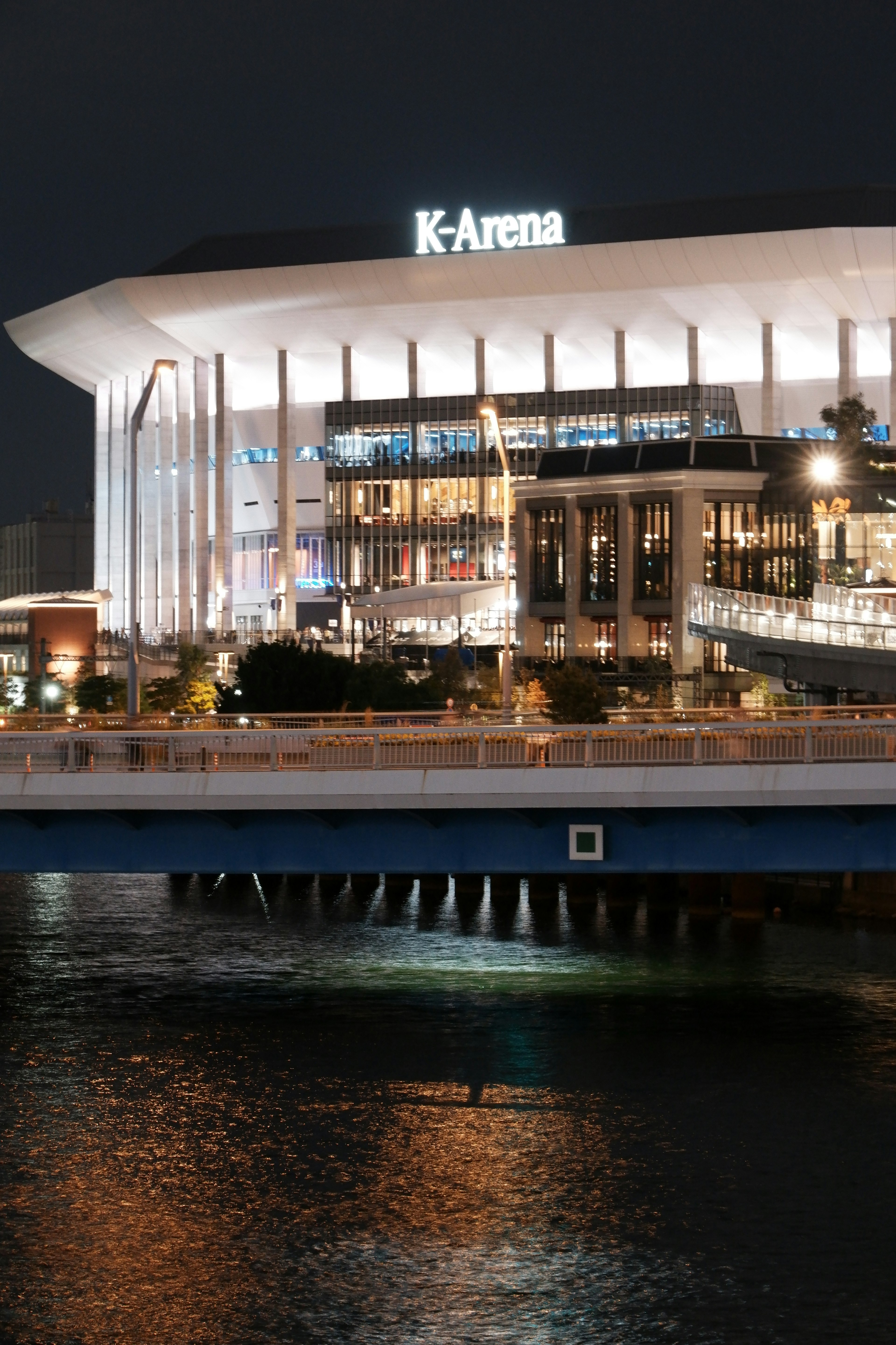 Nachtansicht der K-Arena mit Reflexionen auf dem Wasser