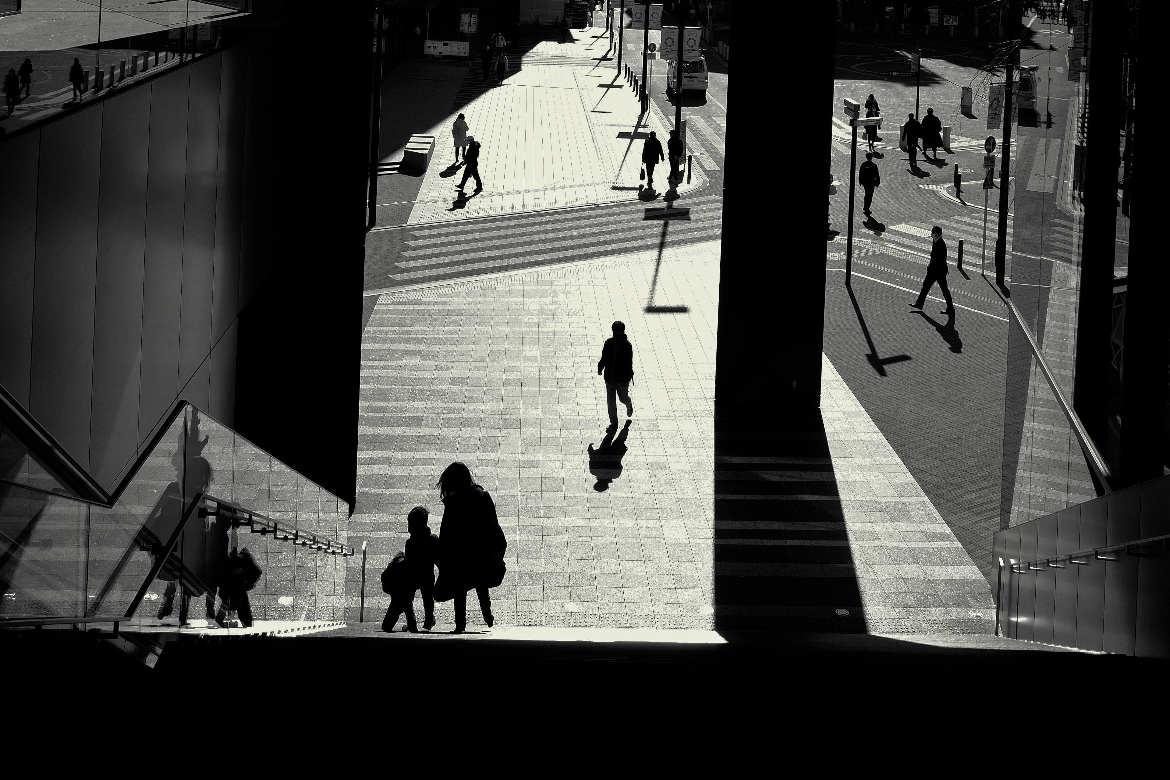 Monochrome urban scene with people walking and shadows cast on the ground