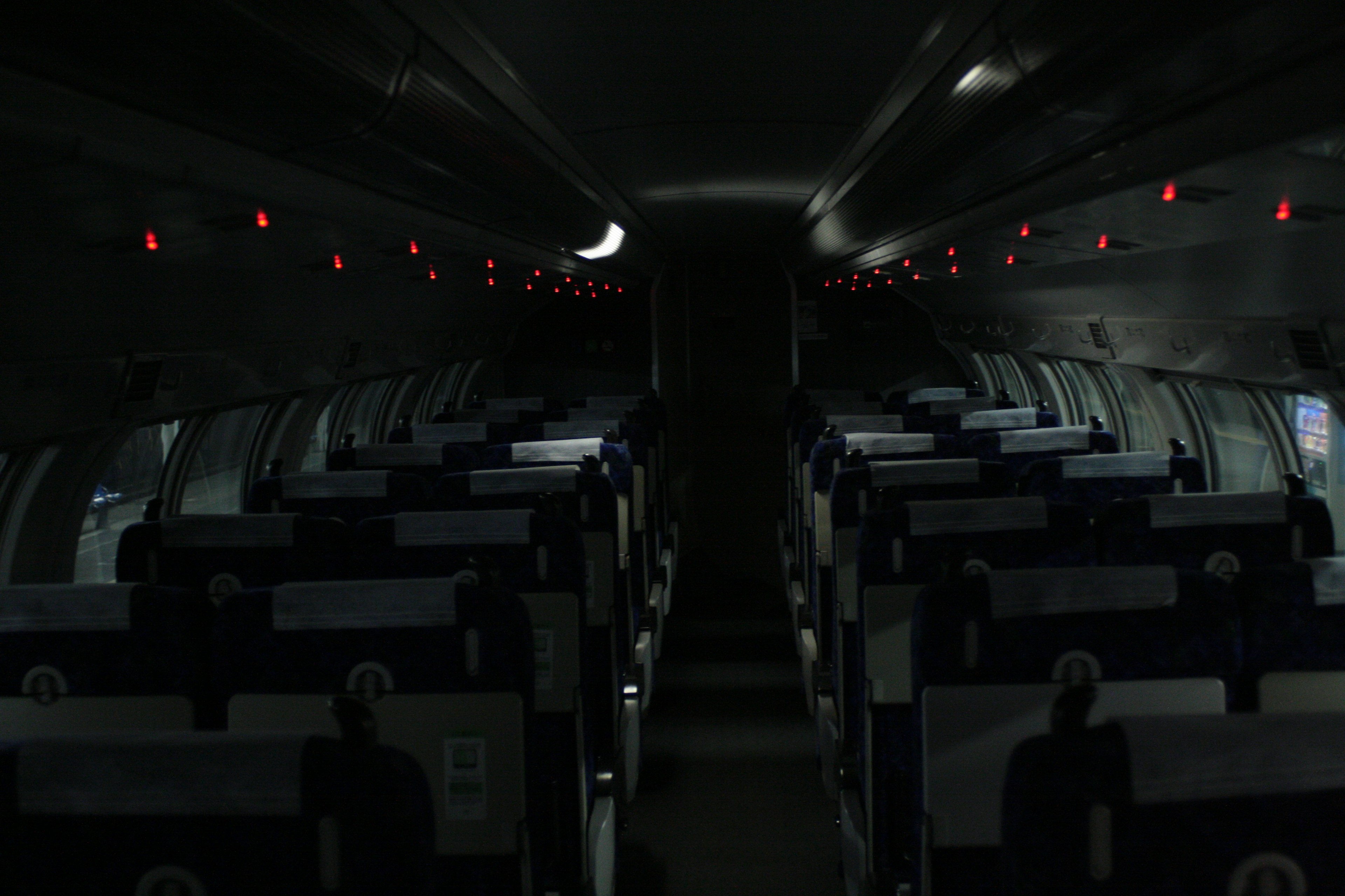 Interior oscuro de la cabina del avión con luces rojas iluminadas y filas de asientos