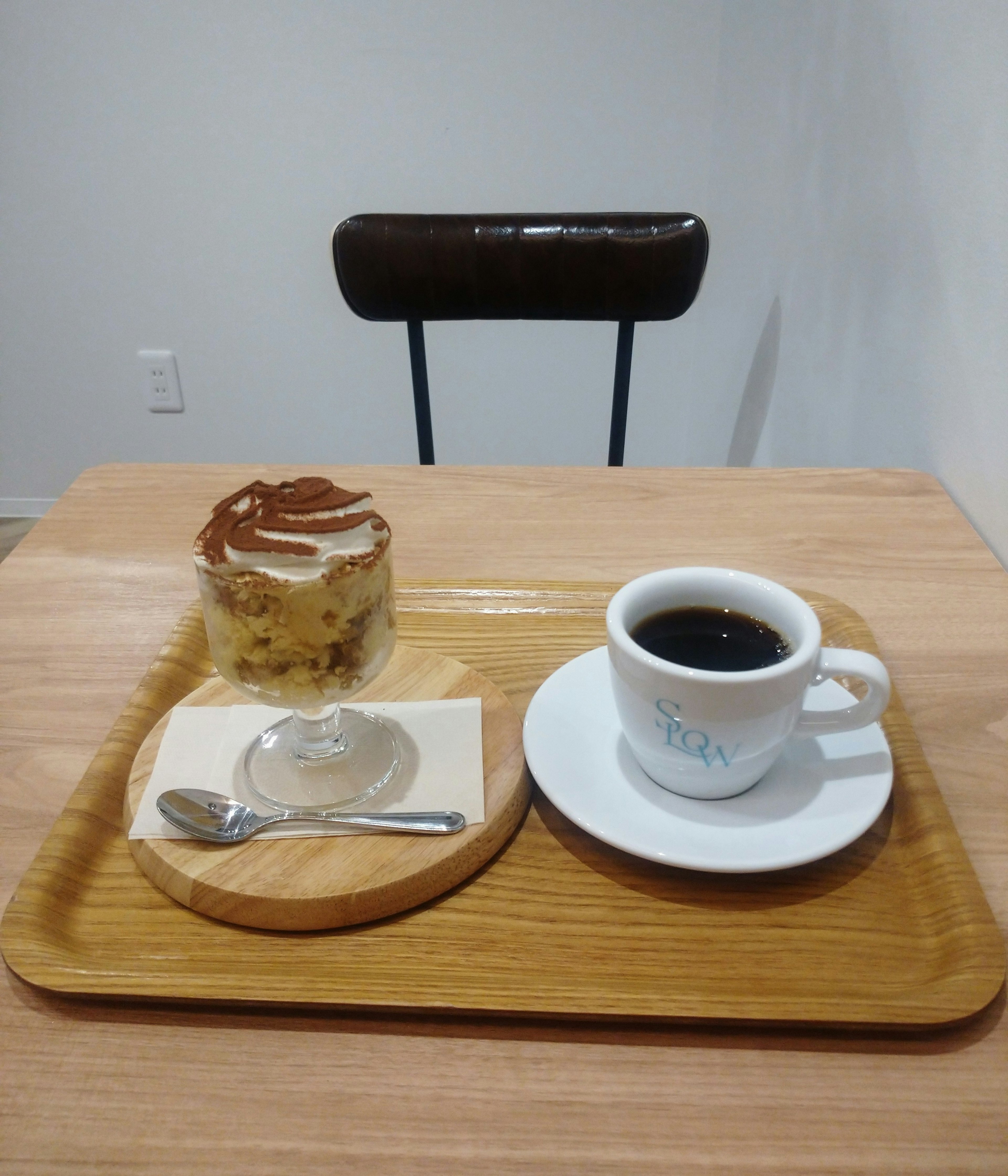 A coffee cup and dessert on a wooden tray at a minimalist cafe