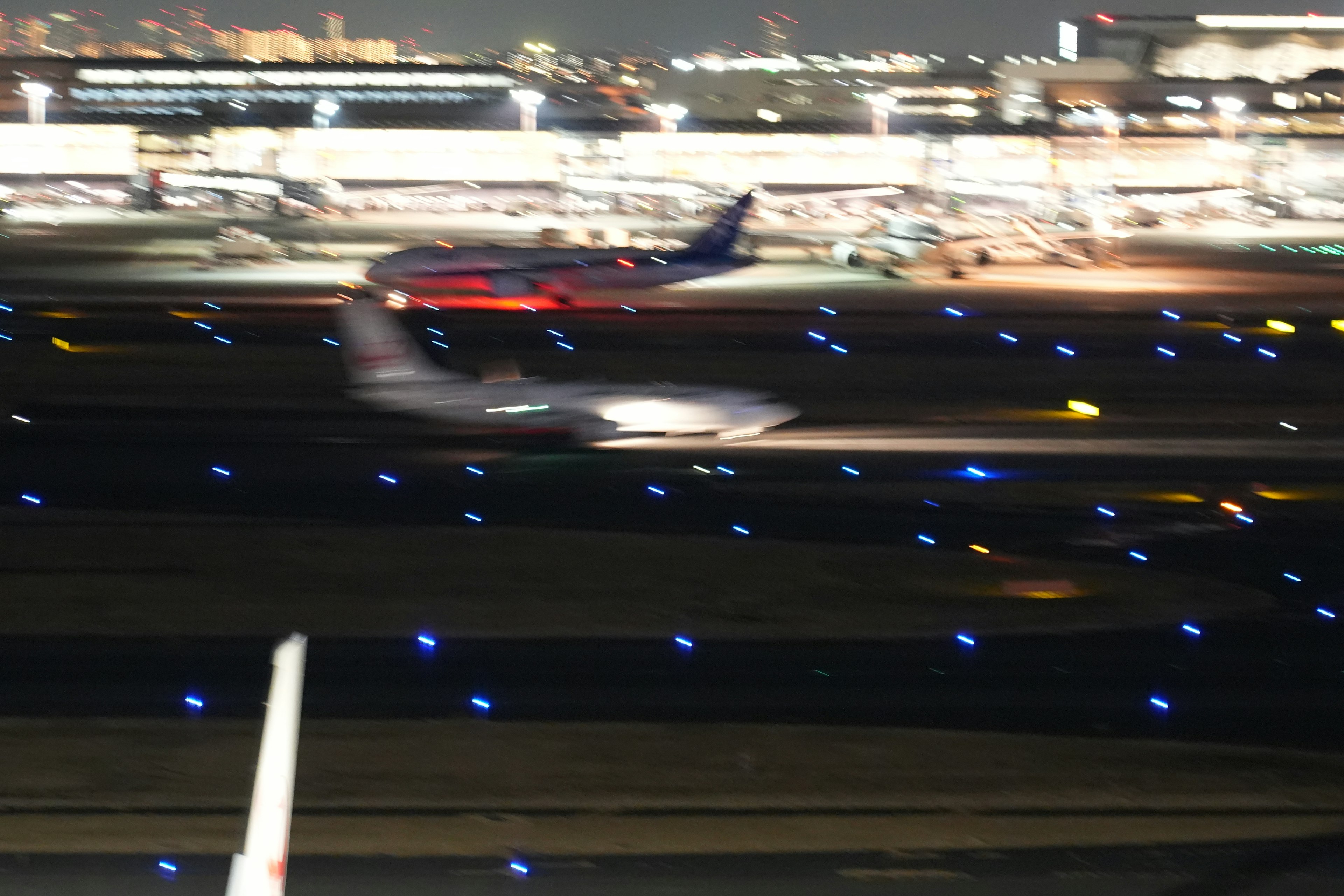 Flugzeuge auf der Piste bei Nacht mit hellen Pistenlichtern