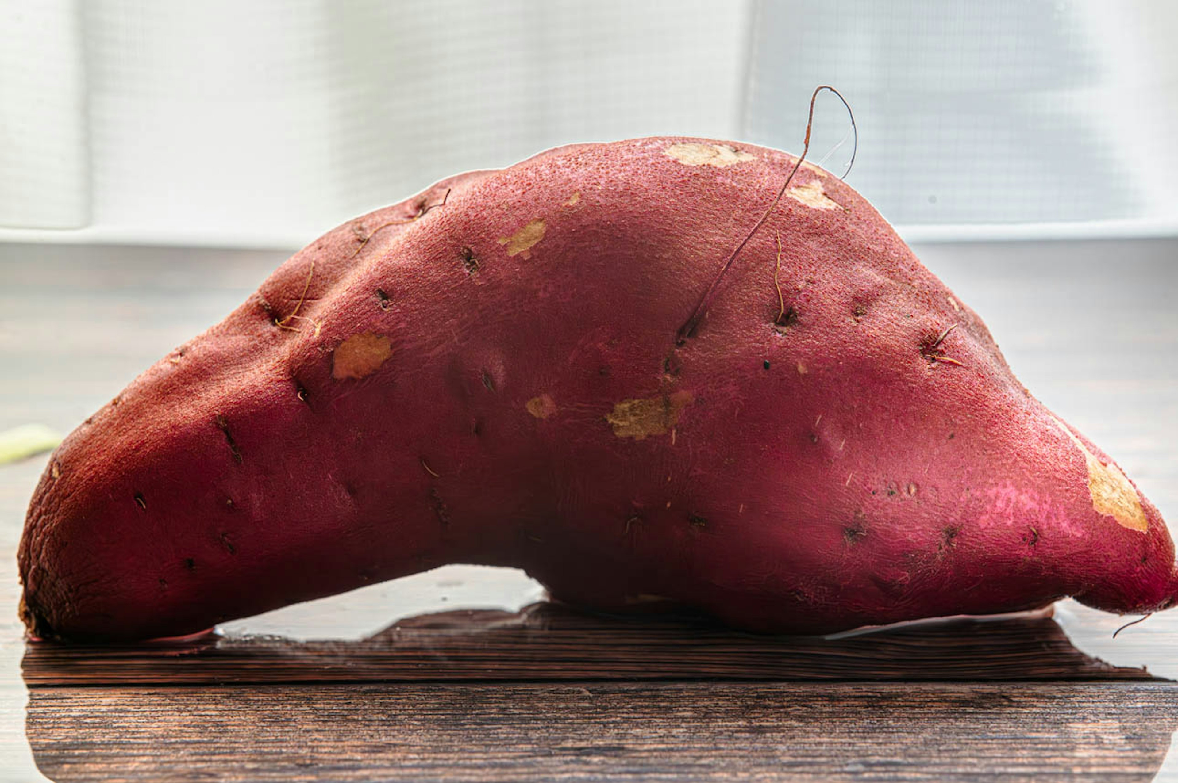 Image d'une patate douce rouge sur une table en bois