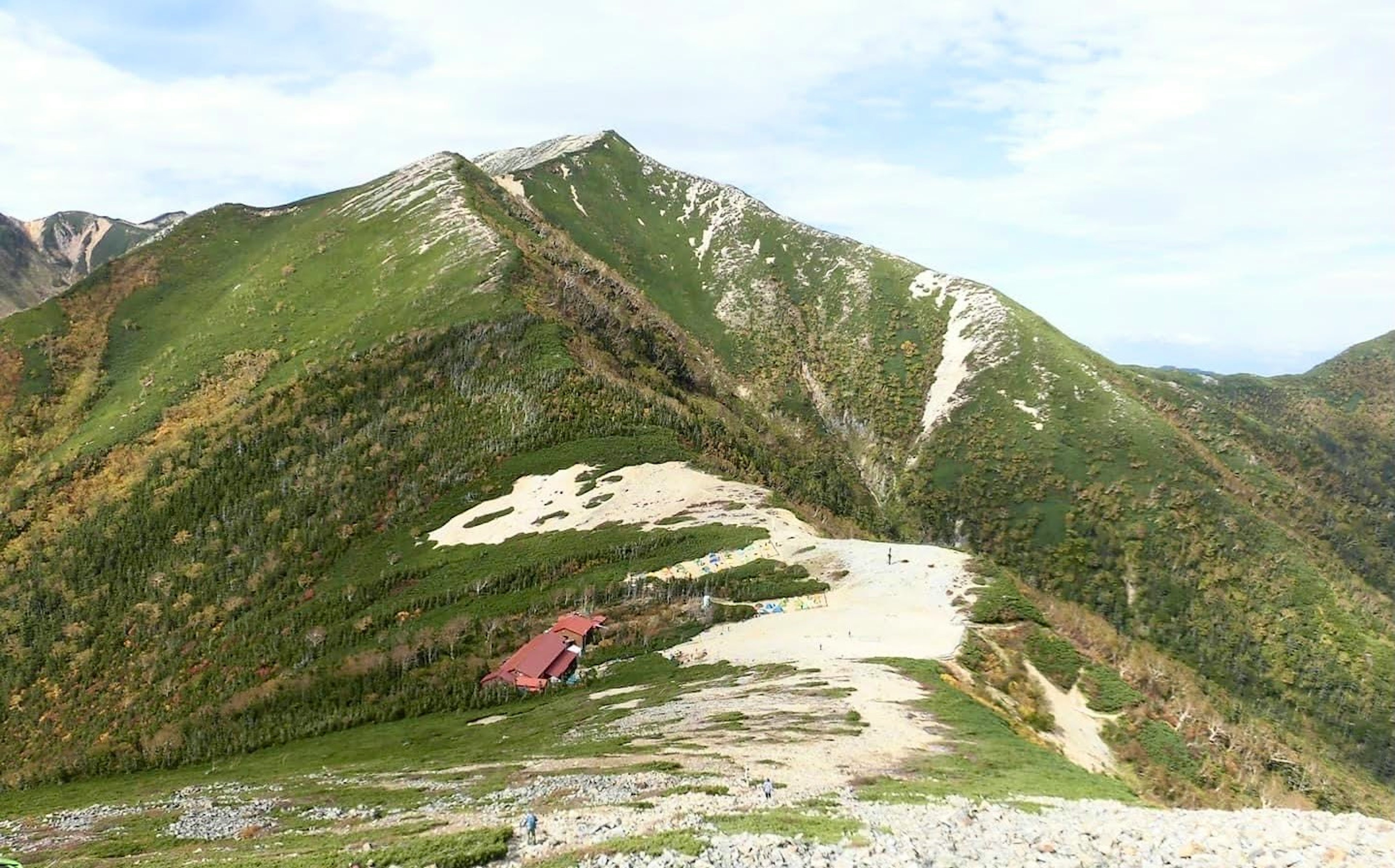 緑豊かな山々と白い雪の残る斜面が広がる風景