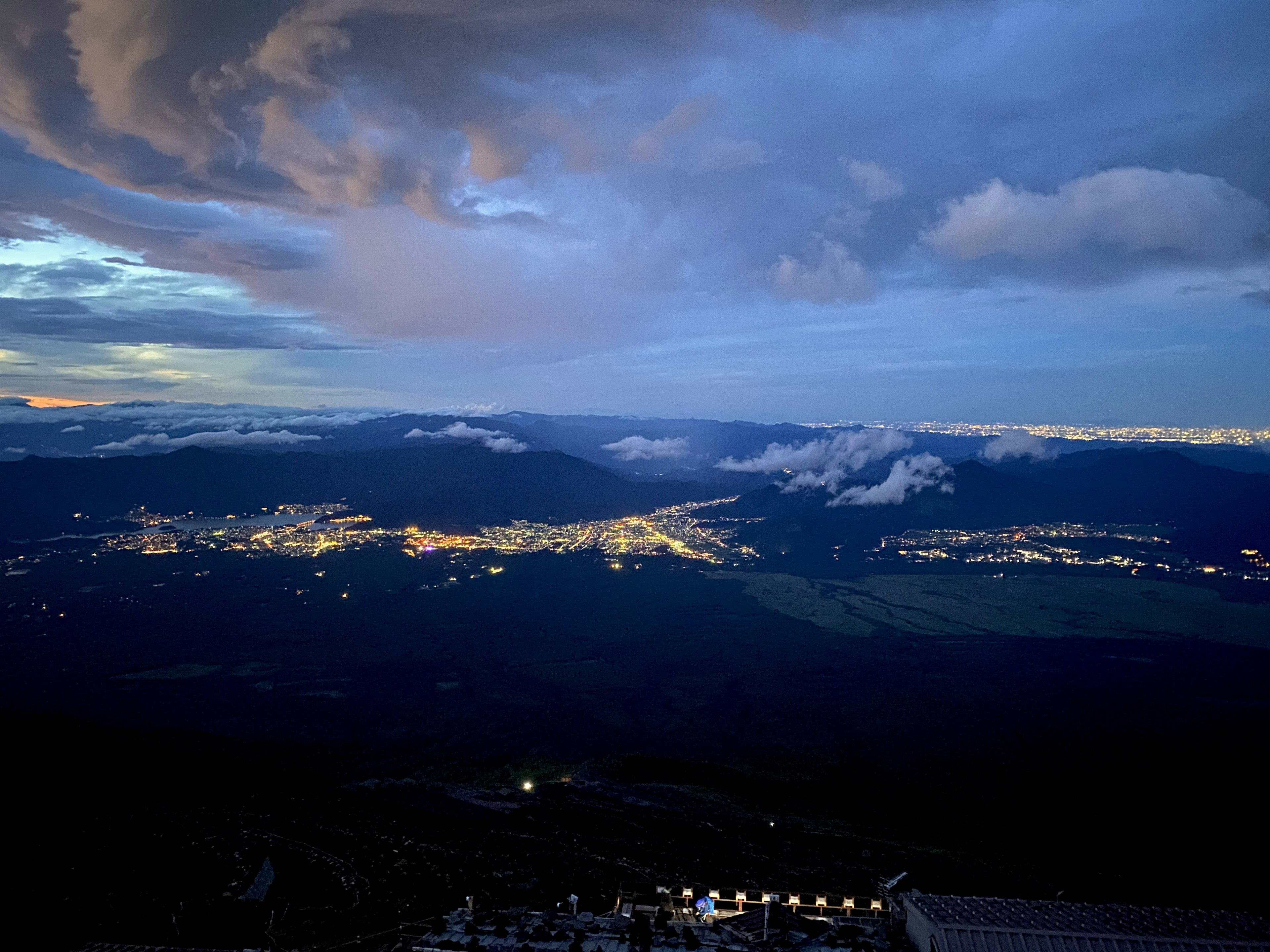 Night view of a city illuminated under a blue sky and clouds