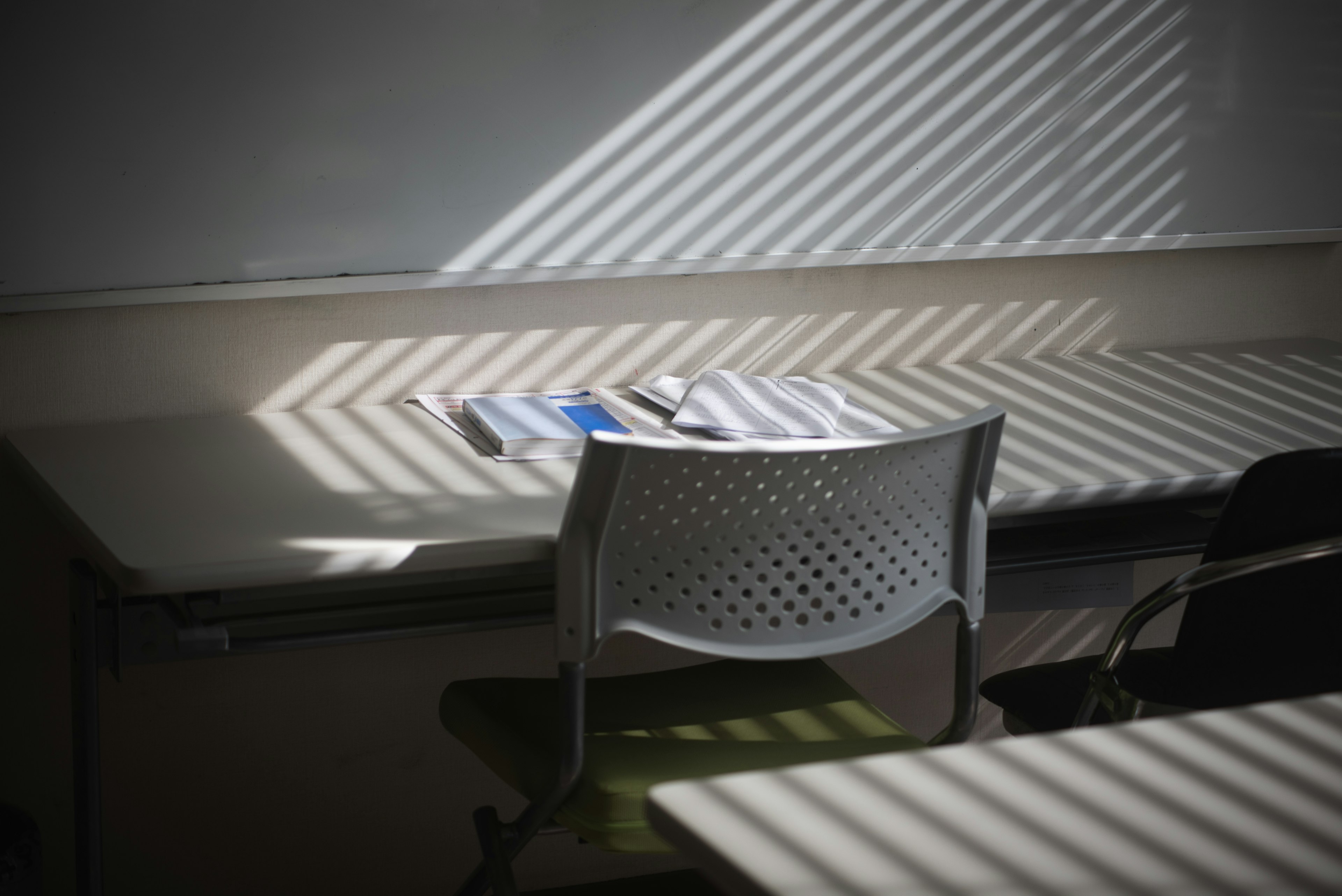 Schreibtisch und Stuhl im Klassenzimmer mit gestreiften Schatten