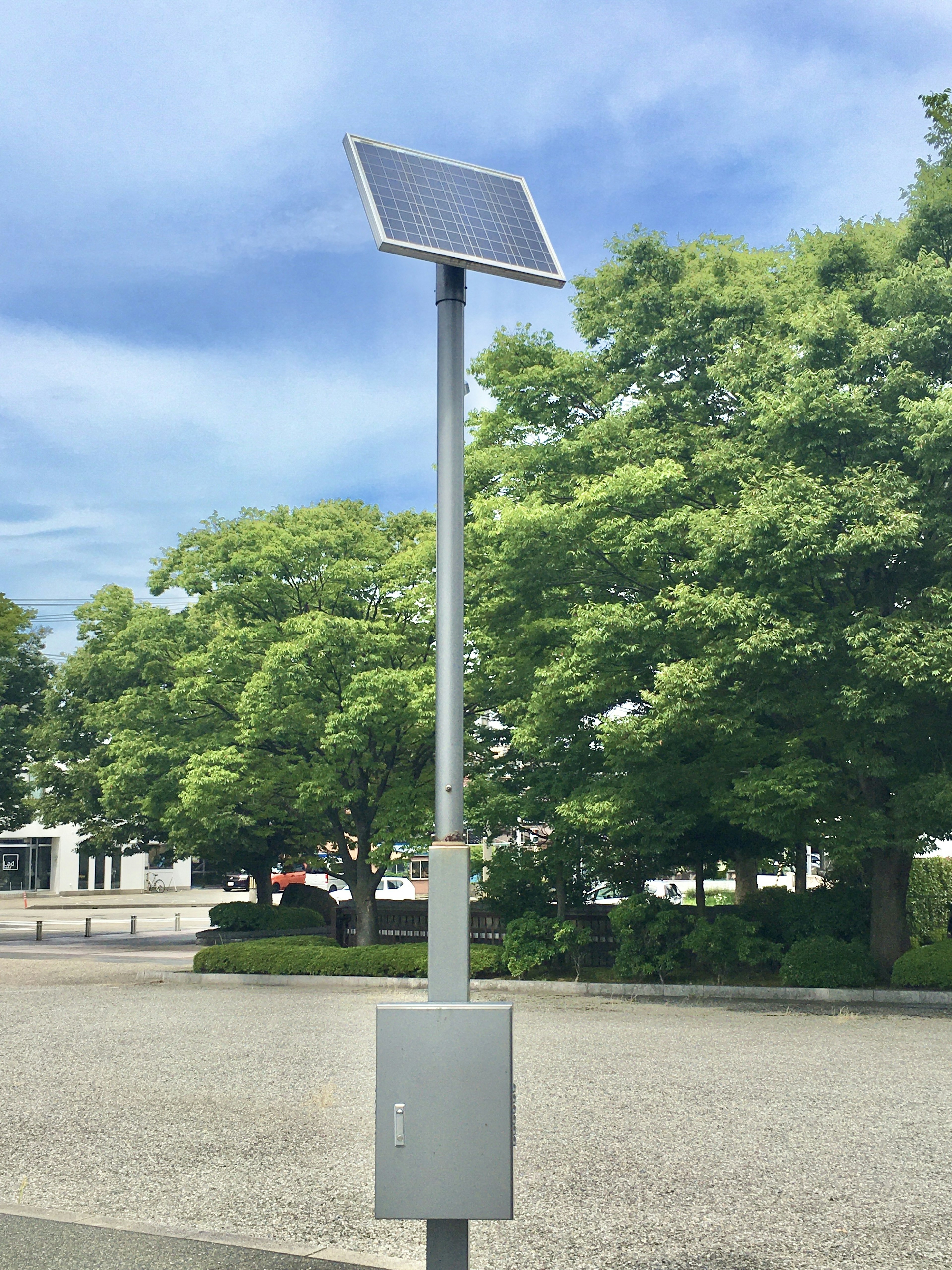 A streetlight with a solar panel standing in a park