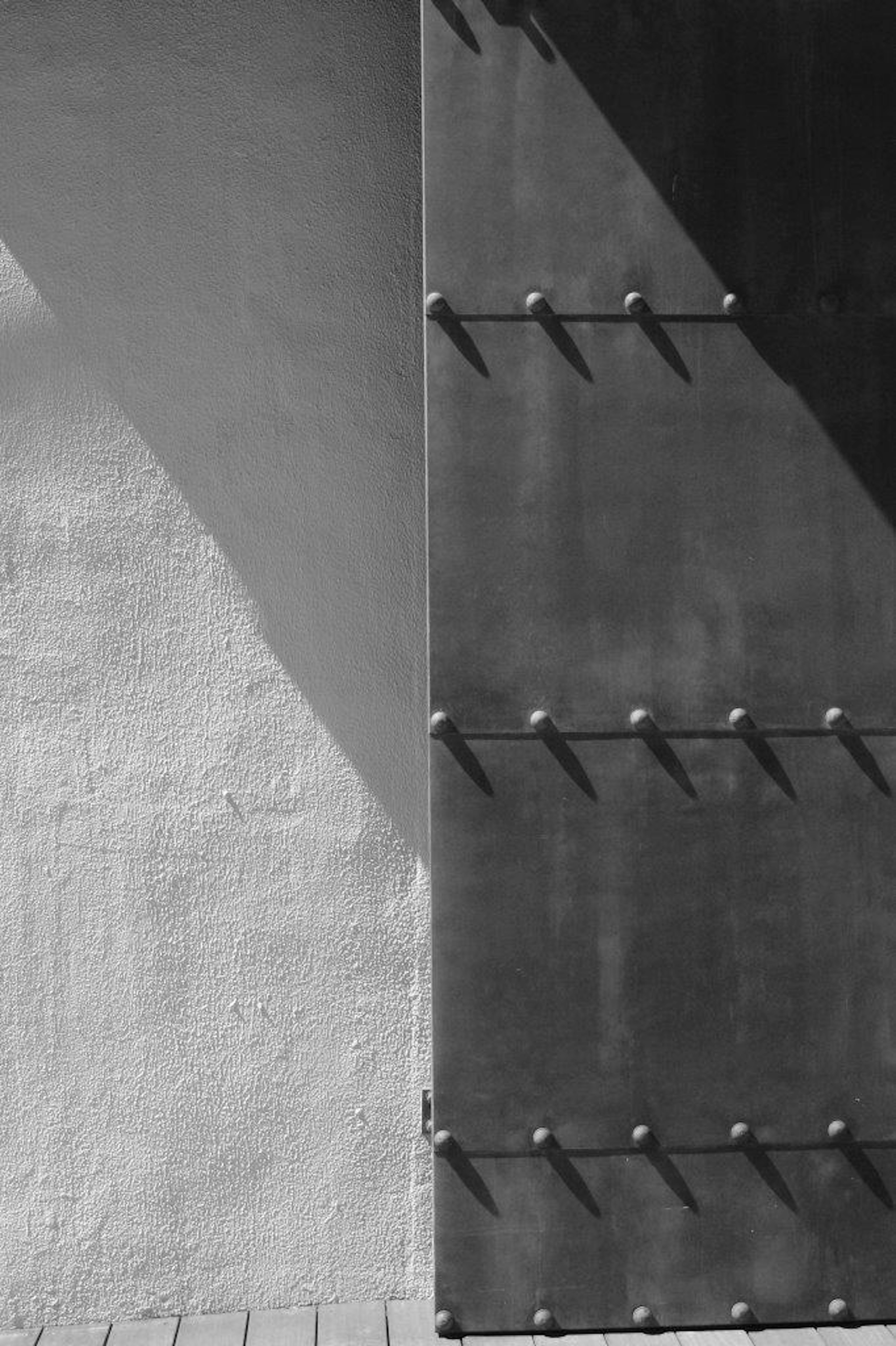 Vista parcial de una puerta de metal y una pared con tonos contrastantes en blanco y negro