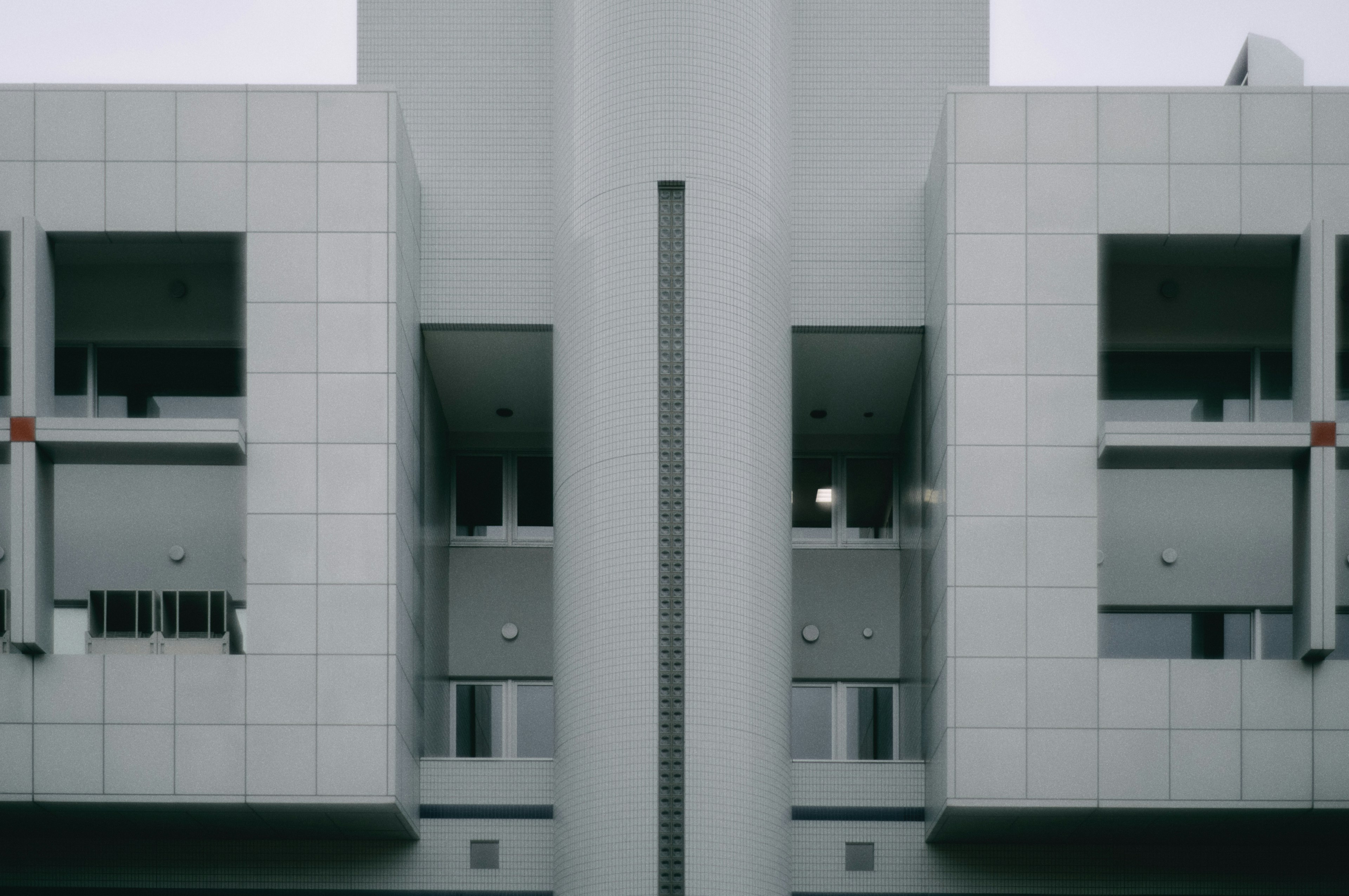 Fachada simétrica de un edificio de azulejos blancos con ventanas y balcones