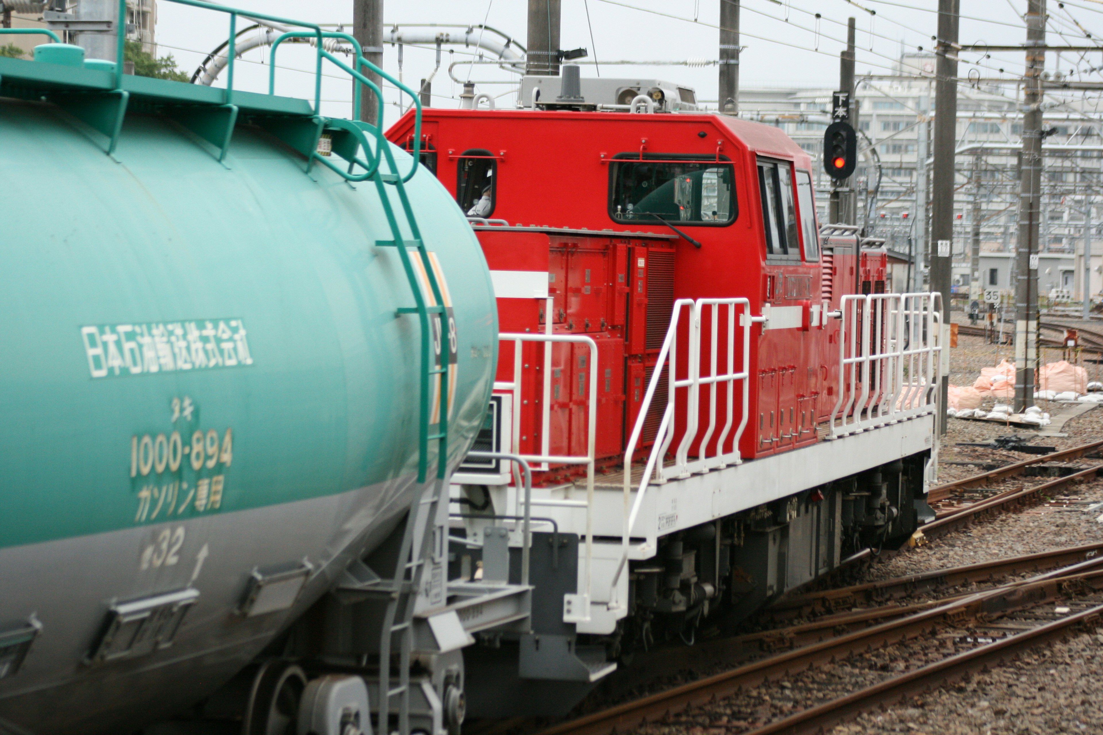 赤い機関車が緑の貨車の横を通過している風景