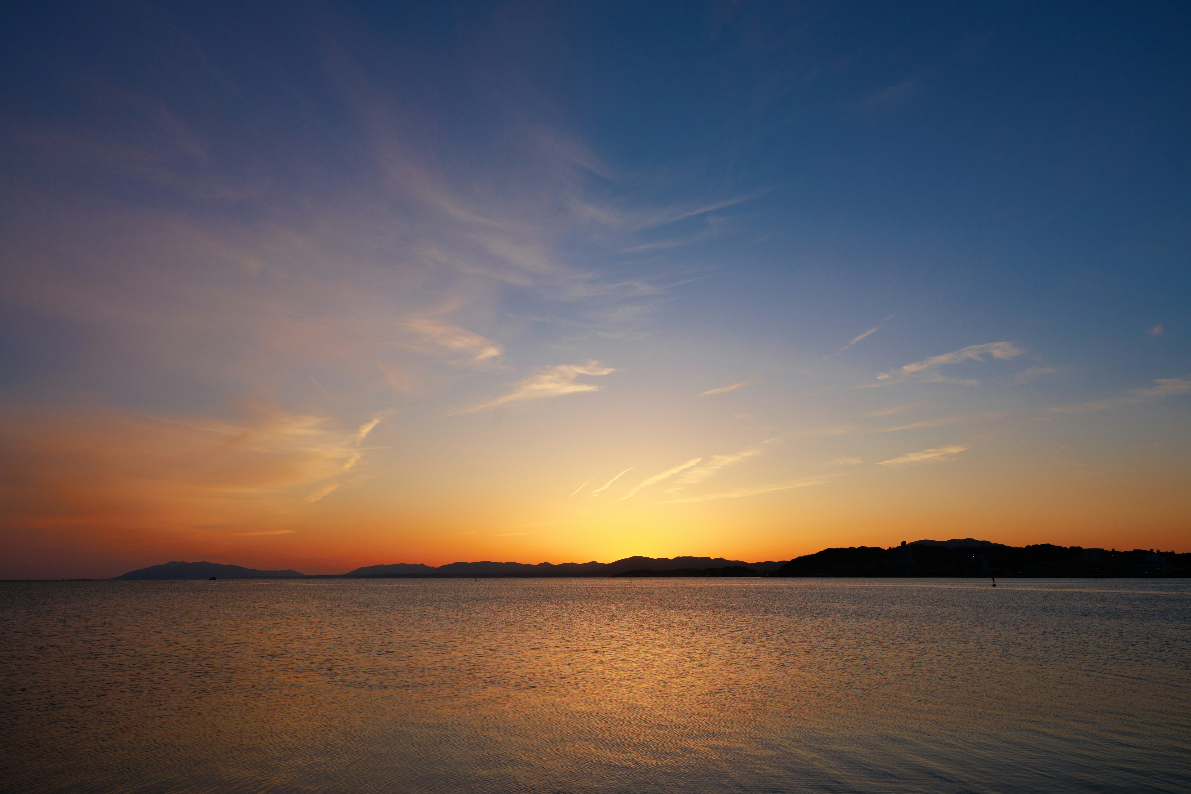 Wunderschöner Sonnenuntergang über dem Meer mit blauem Himmel und orangefarbenen Tönen