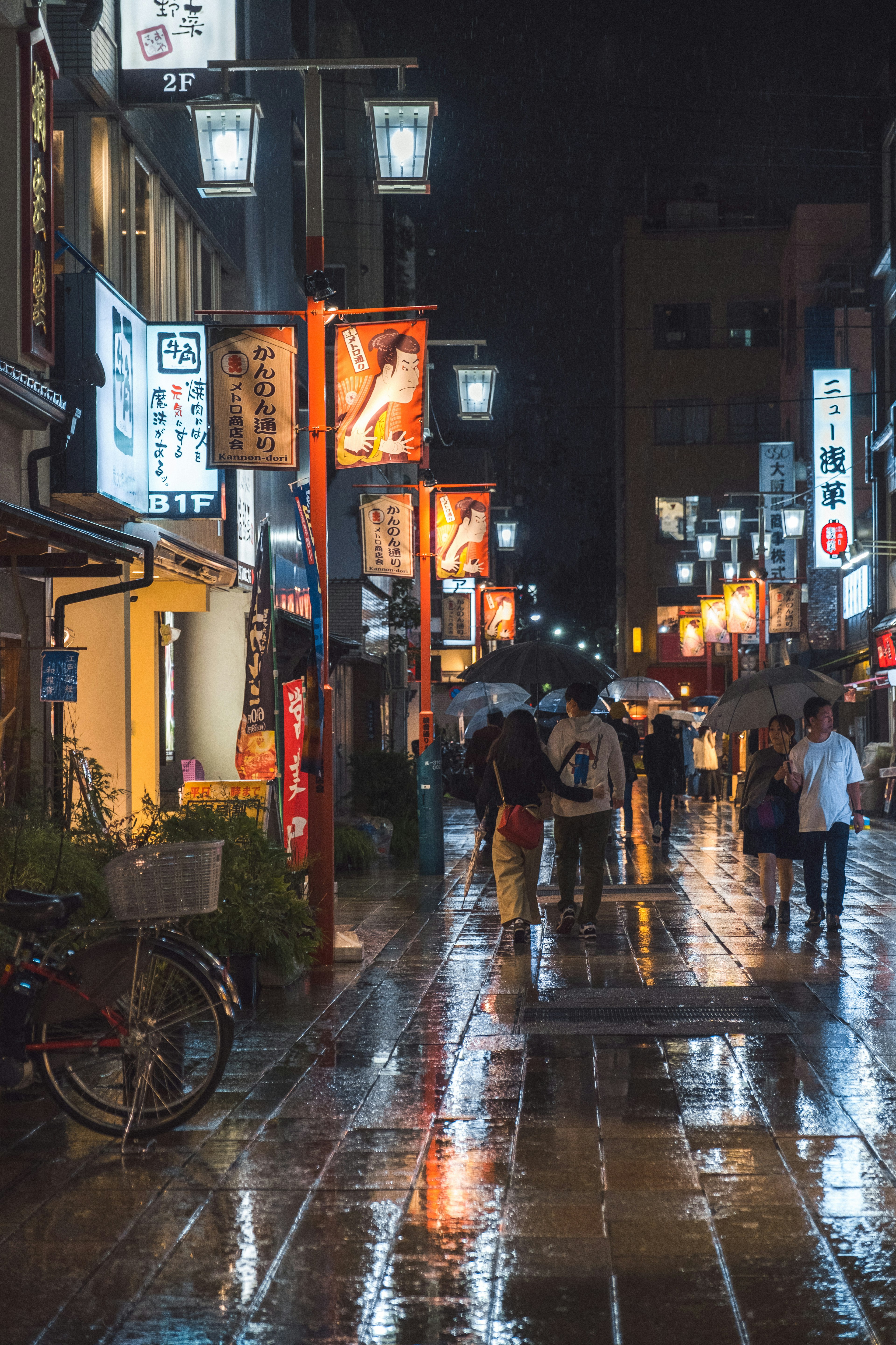 Scène de rue nocturne avec des personnes marchant sous la pluie