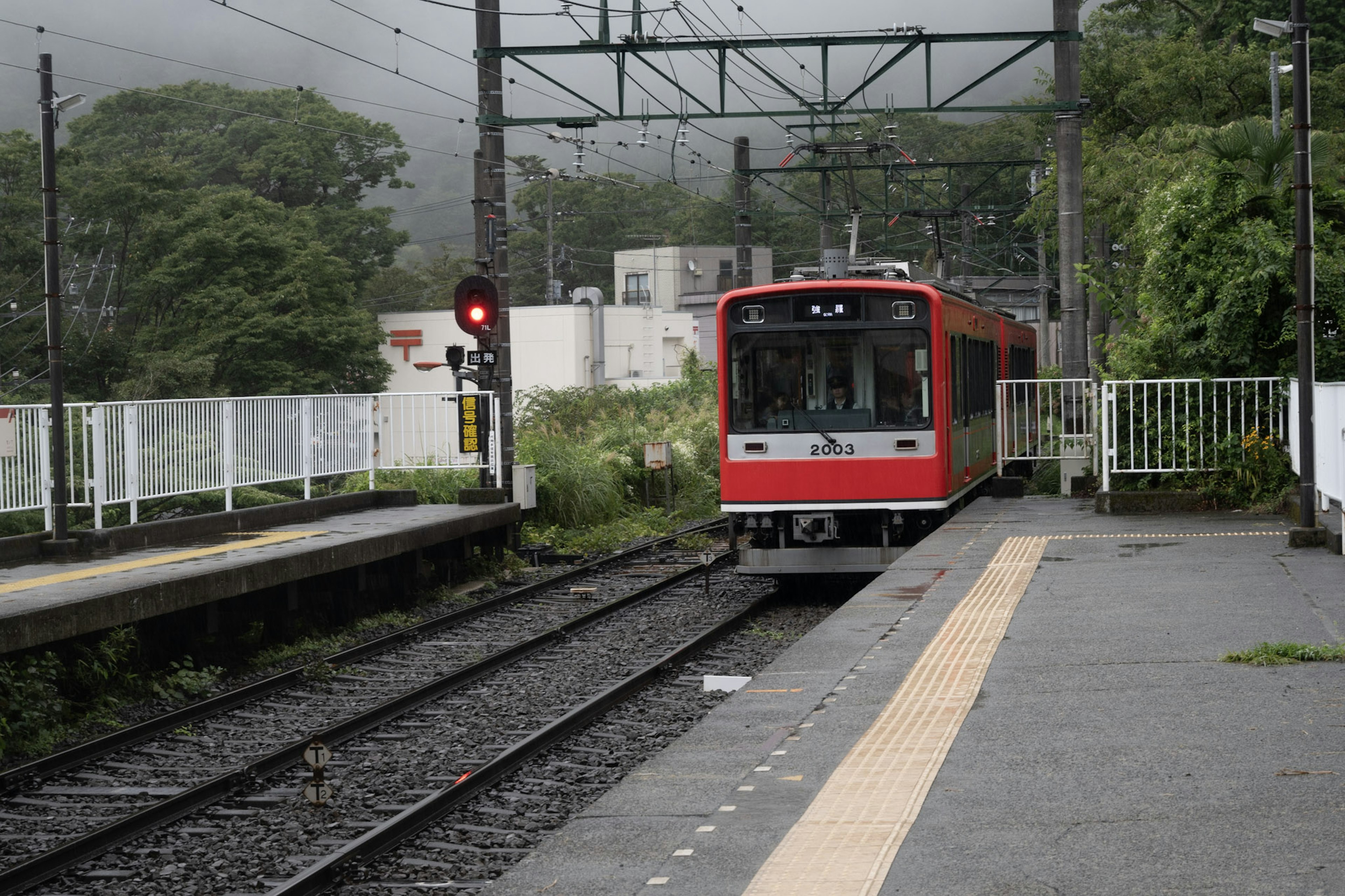 赤い電車が駅に停車している風景 線路と信号機が見える