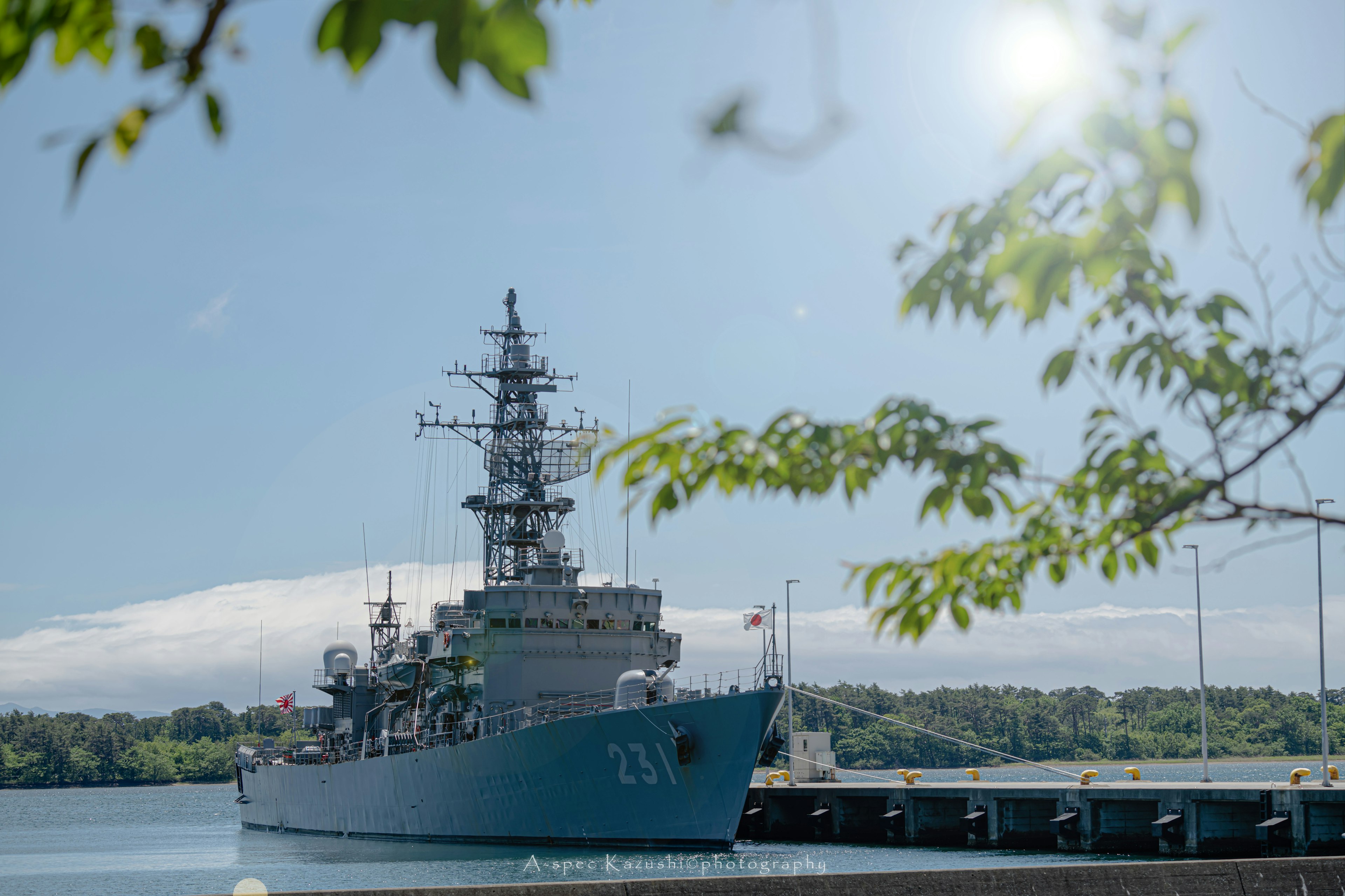 A blue naval ship docked at a harbor under a clear sky