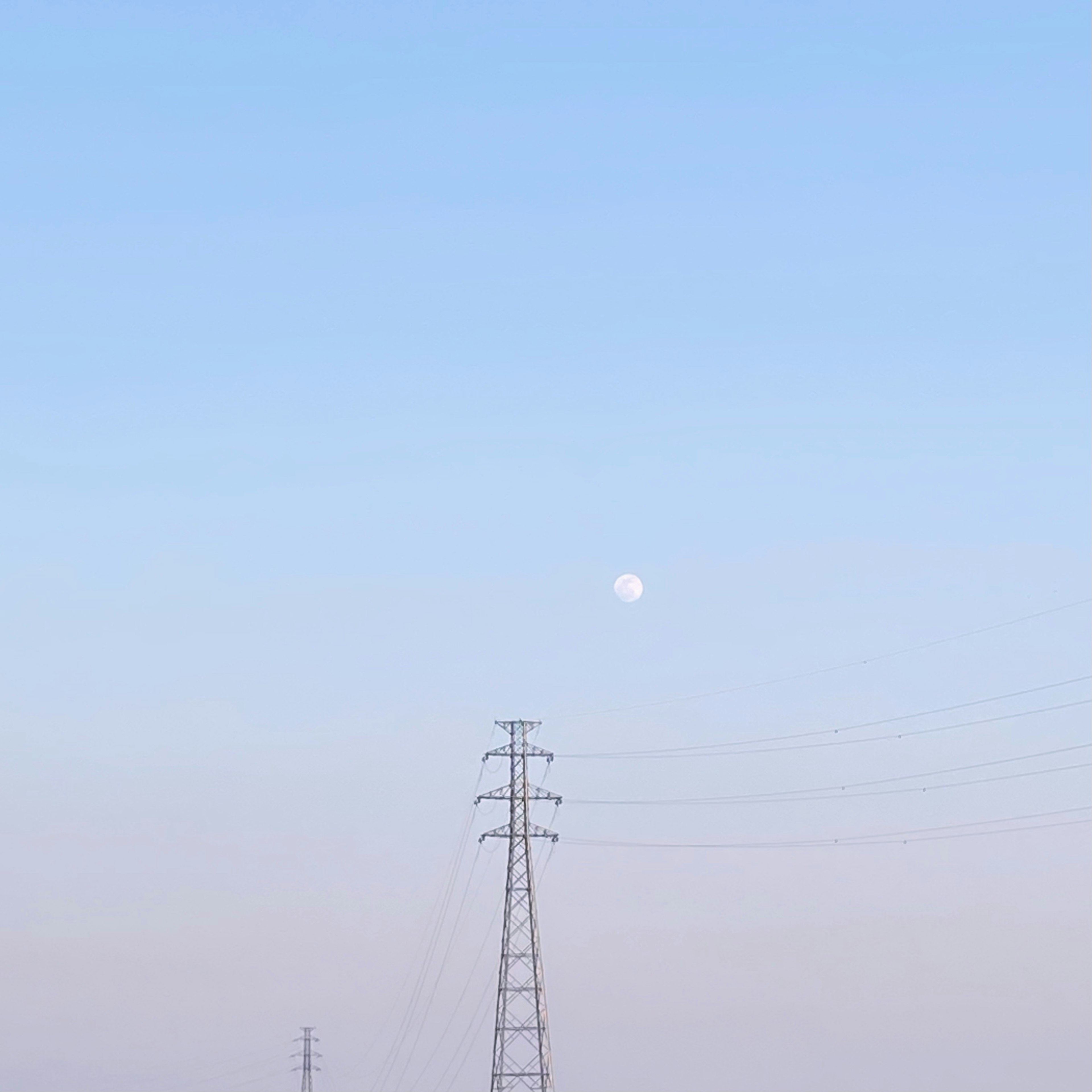 Mond in einem blauen Himmel mit Silhouetten von Stromleitungen