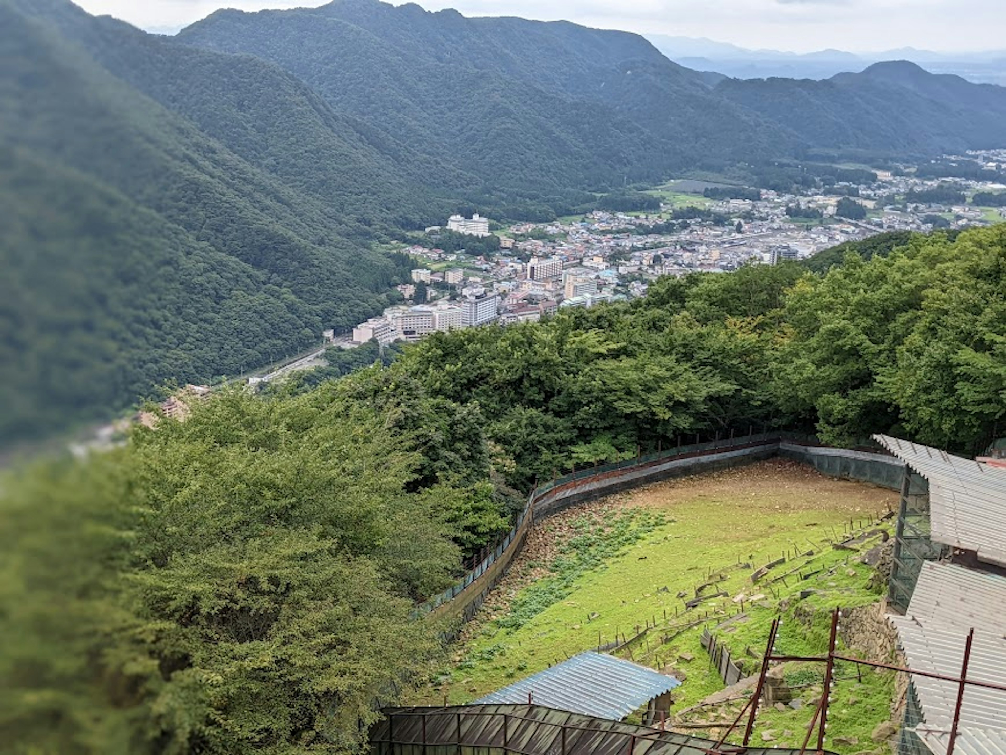 View of a town surrounded by mountains with lush green land and visible buildings